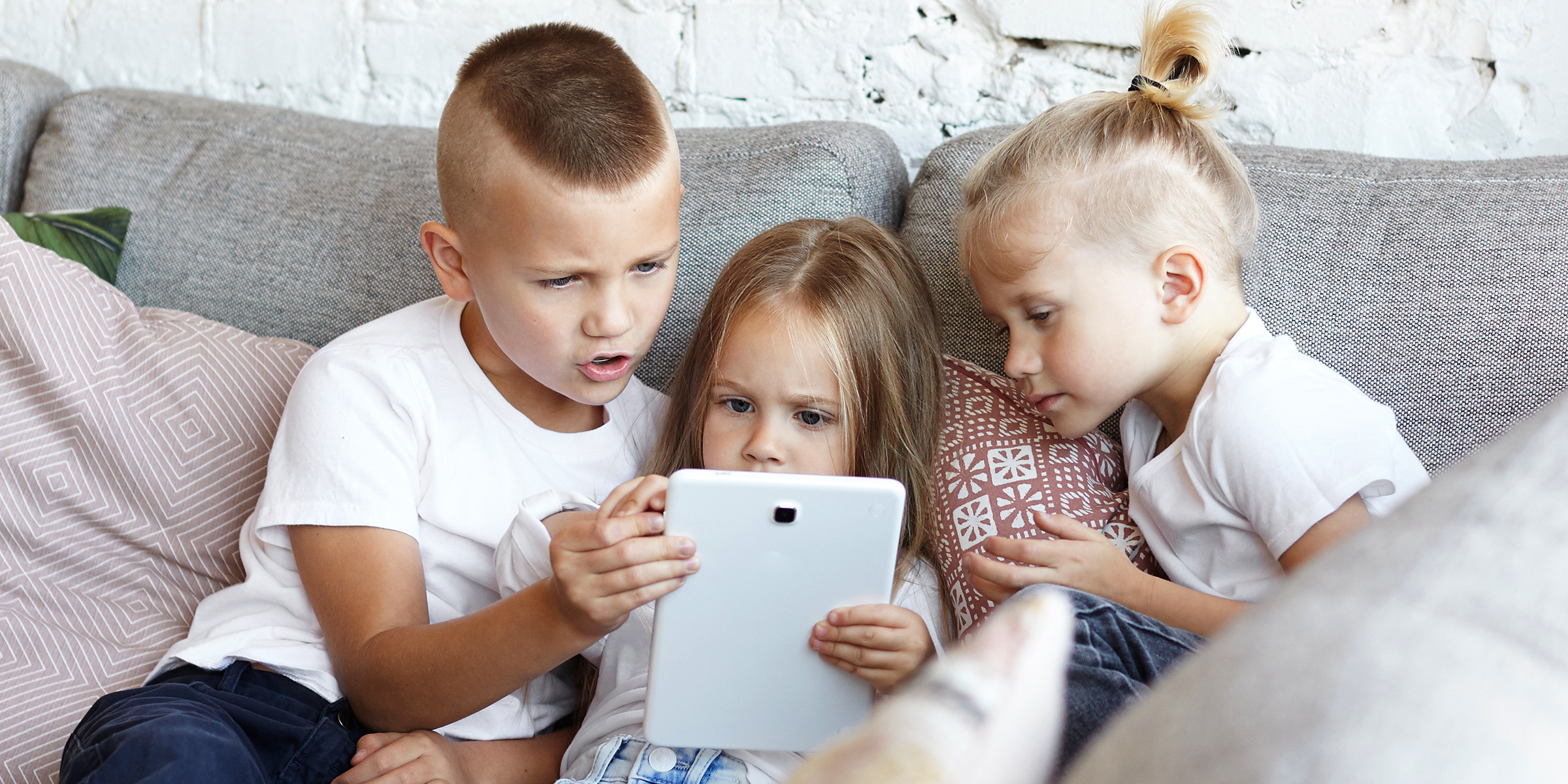 Drei Kinder sitzen auf einer Couch | Quelle: Shutterstock