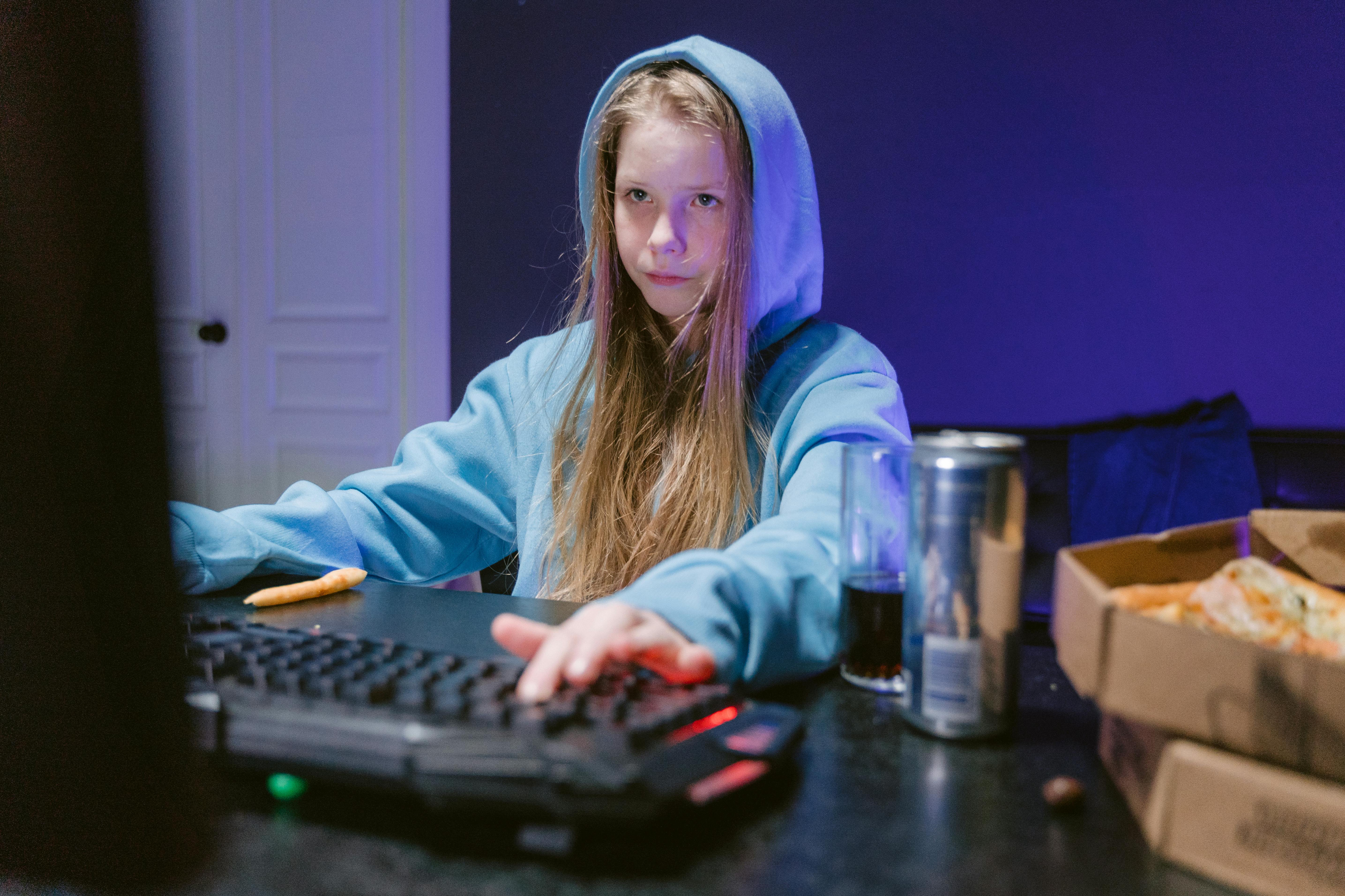 Ein Mädchen an einem Computer in ihrem Zimmer mit Getränken und Essen zur Hand | Quelle: Pexels