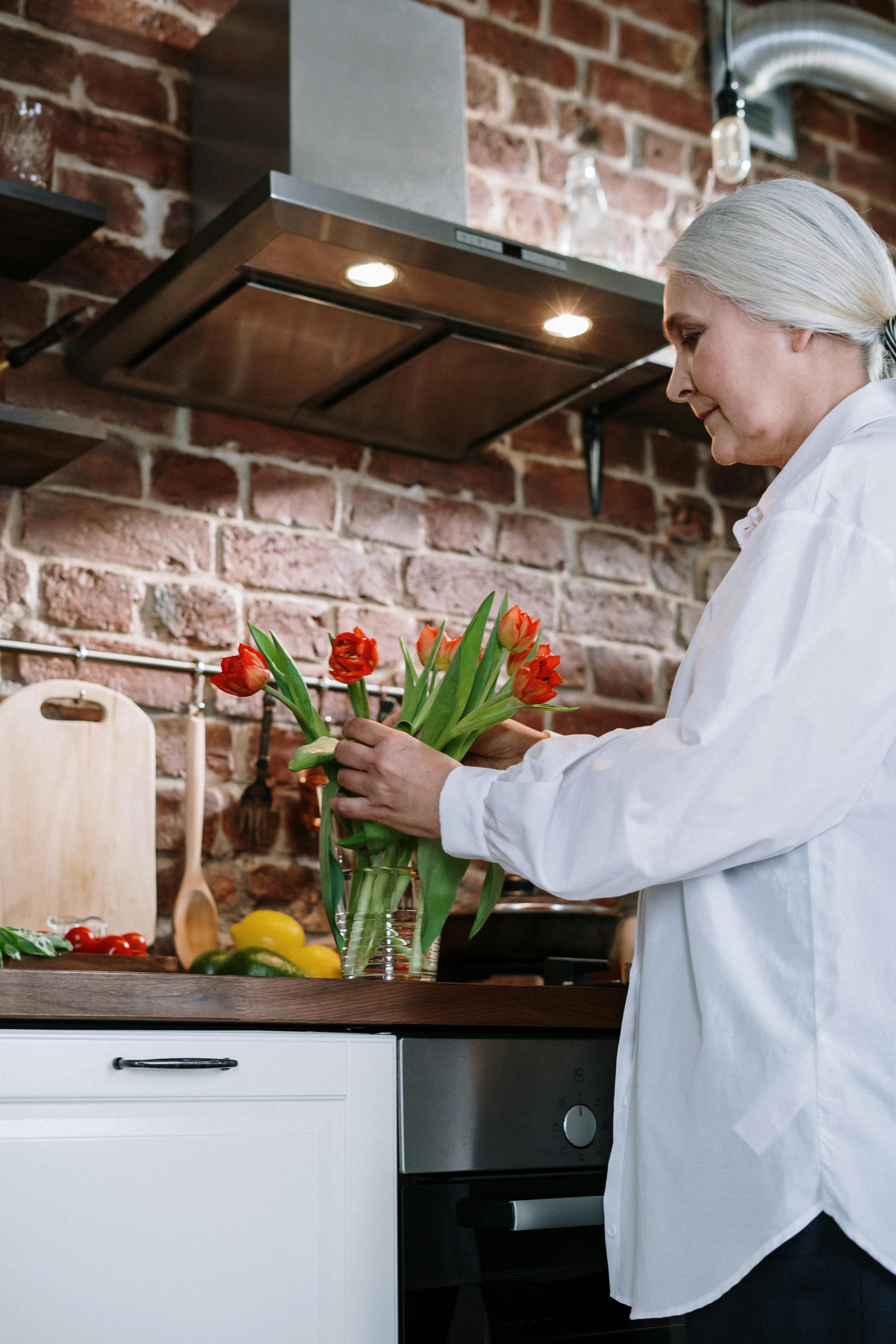 Frau arrangiert Blumen in einer Vase | Quelle: Pexels
