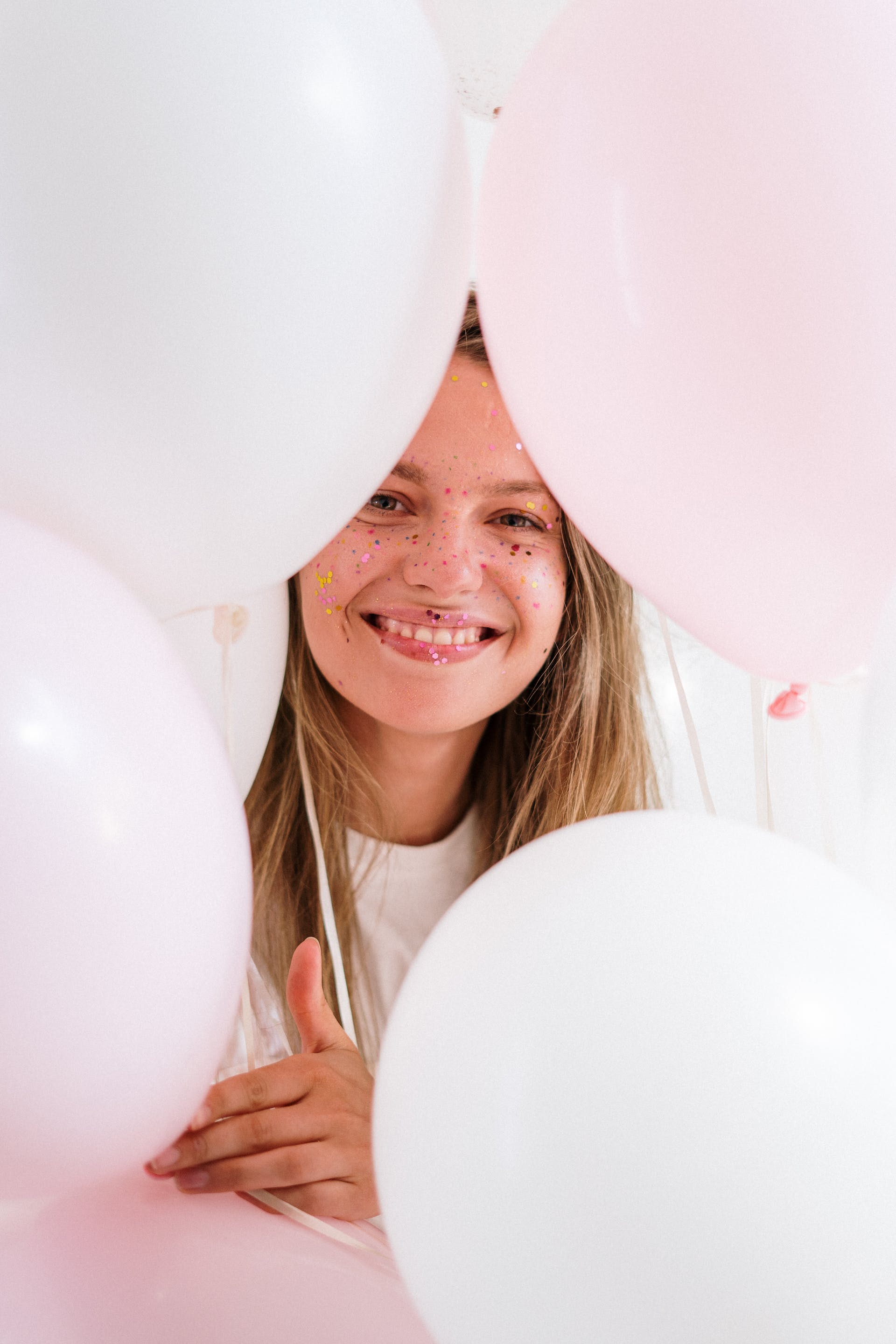 Ein junges Mädchen lächelt, während es Luftballons hält | Quelle: Pexels