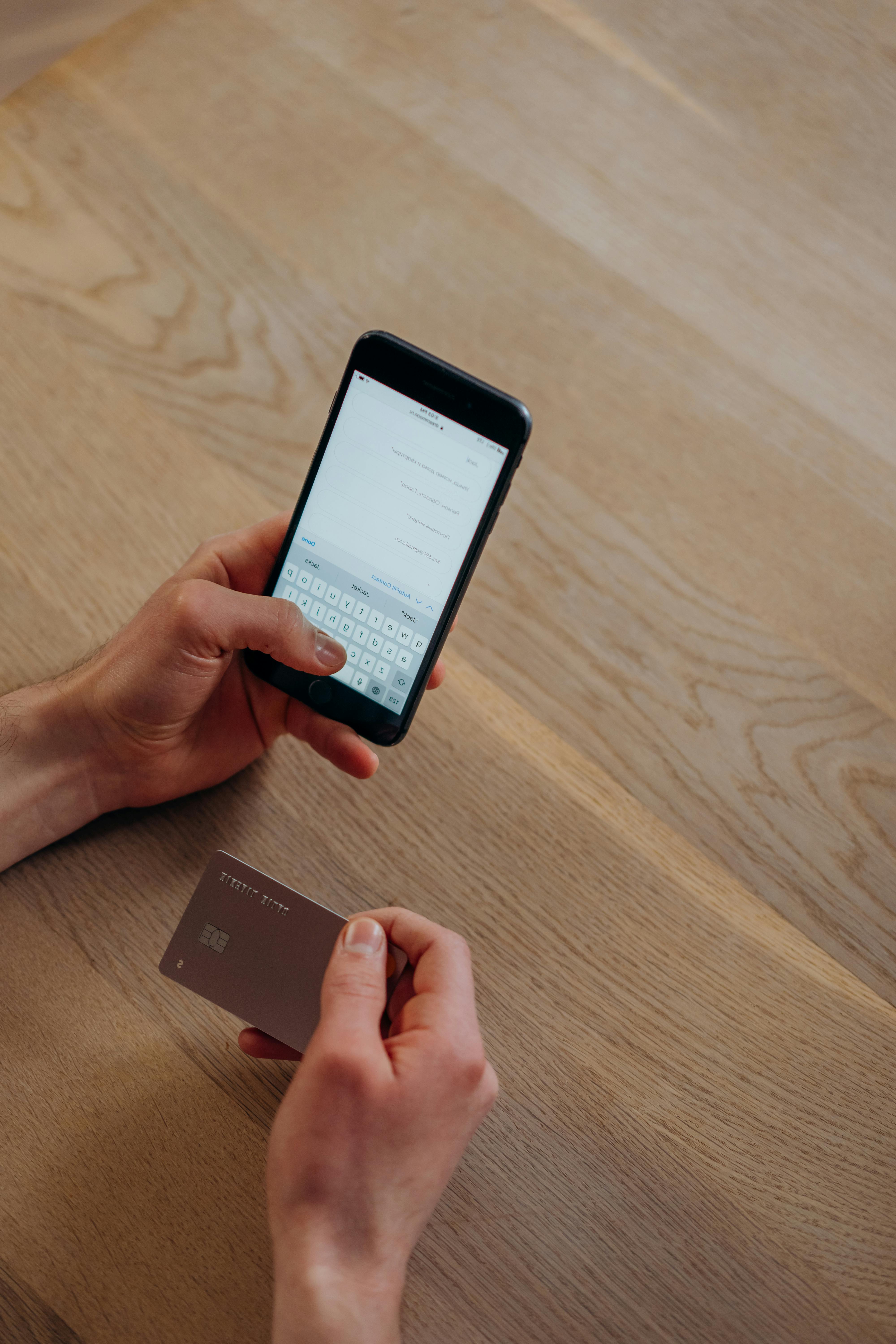 Eine Person, die eine SMS schreibt, während sie eine Kreditkarte hält | Quelle: Pexels