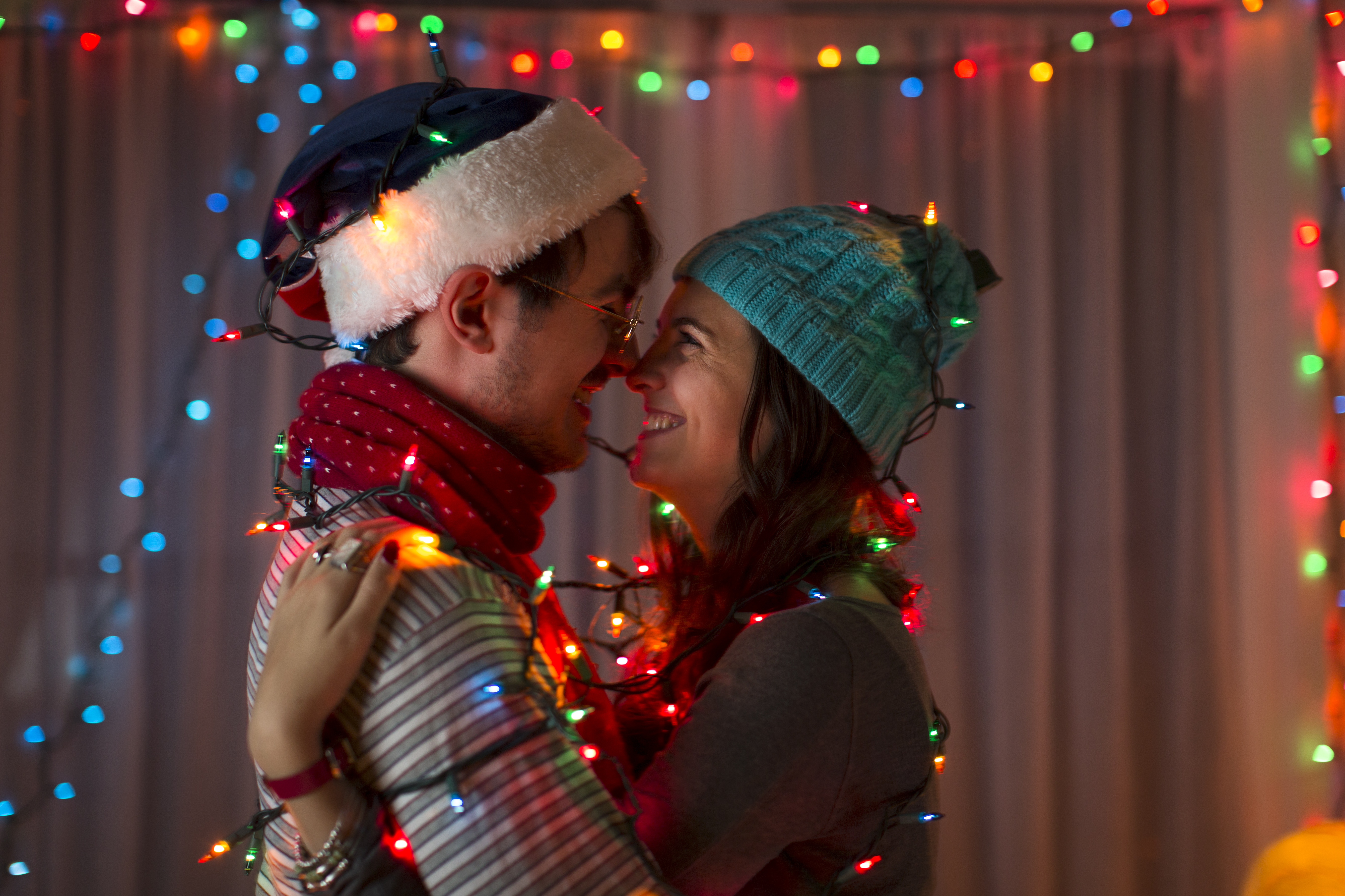 Ein verliebtes Paar, eingewickelt in dekorative Lichter an Weihnachten | Quelle: Getty Images