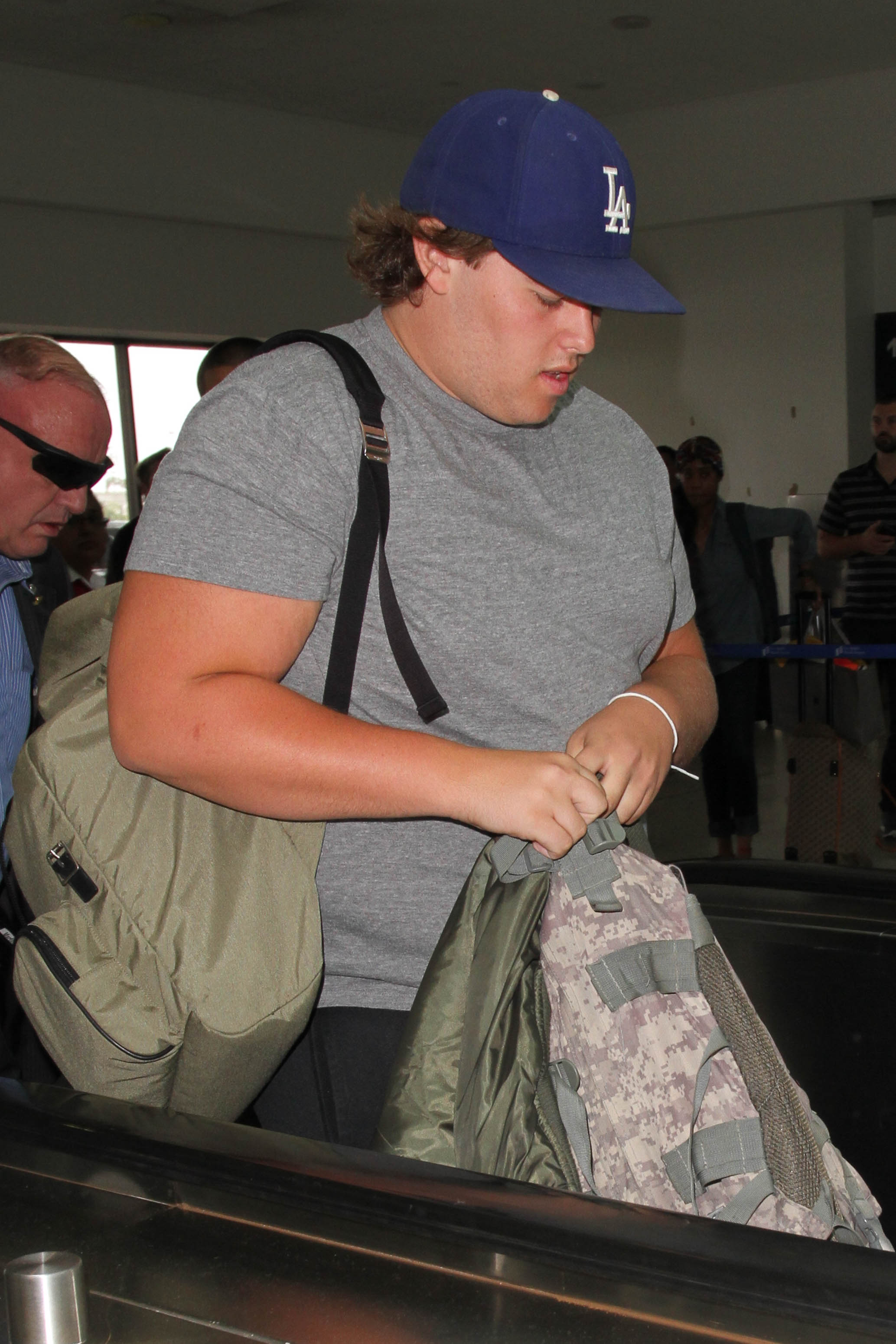 Auf einer anderen Aufnahme vom selben Tag läuft Christopher in lässiger Sportkleidung mit schwarzen Shorts und grauen Turnschuhen aus dem Terminal. Seine Mütze und seine lockere Frisur unterstreichen den lässigen Look, während er sich mit zielstrebigen Schritten bewegt.