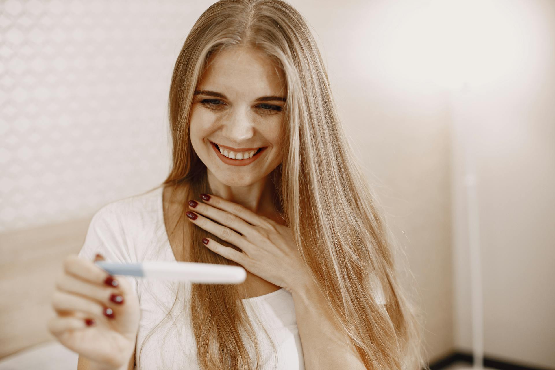 Eine erfreute Frau hält ein Schwangerschaftstest-Kit | Quelle: Pexels