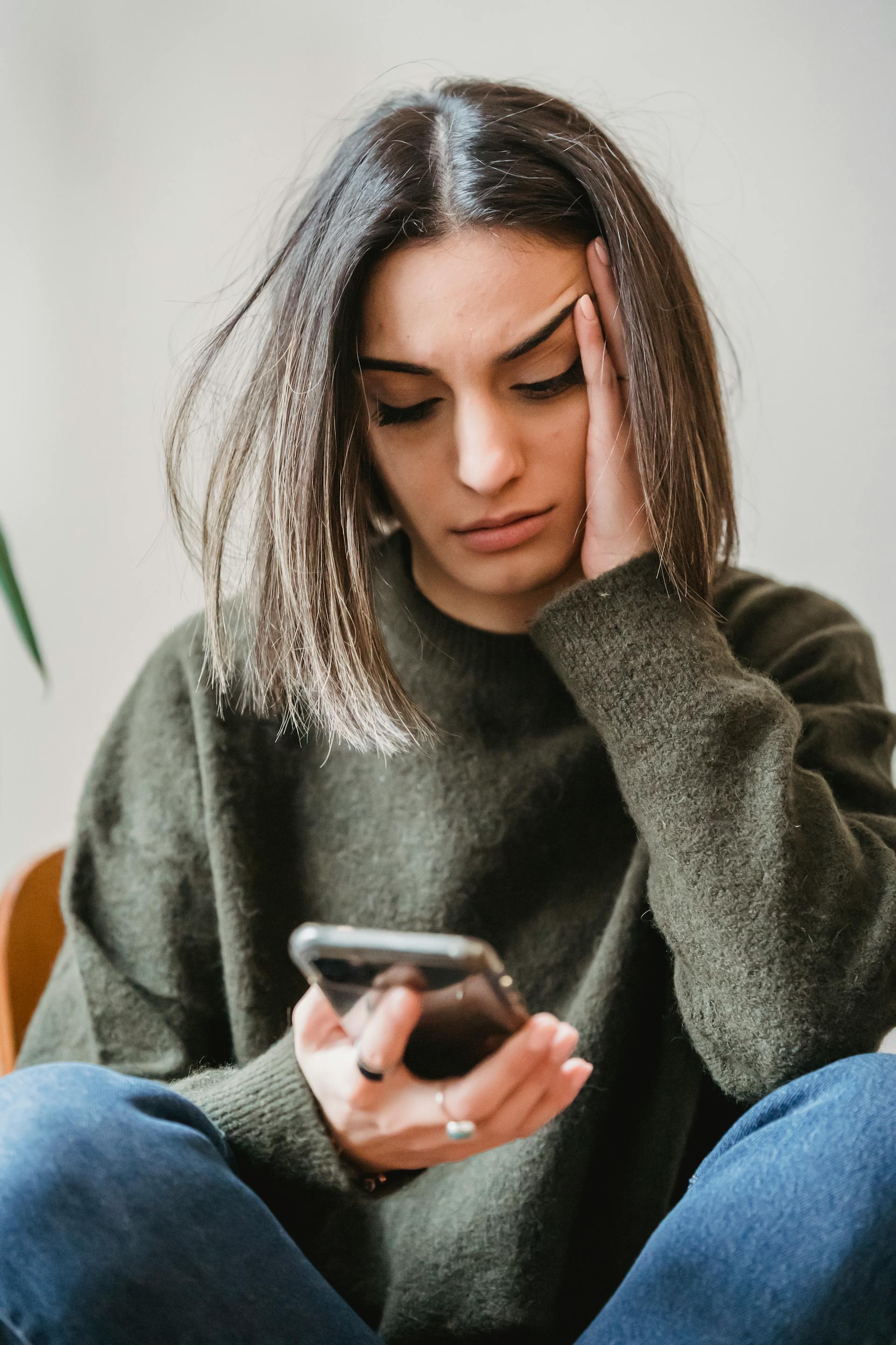 Eine depressive Frau, die auf ihr Telefon schaut | Quelle: Pexels