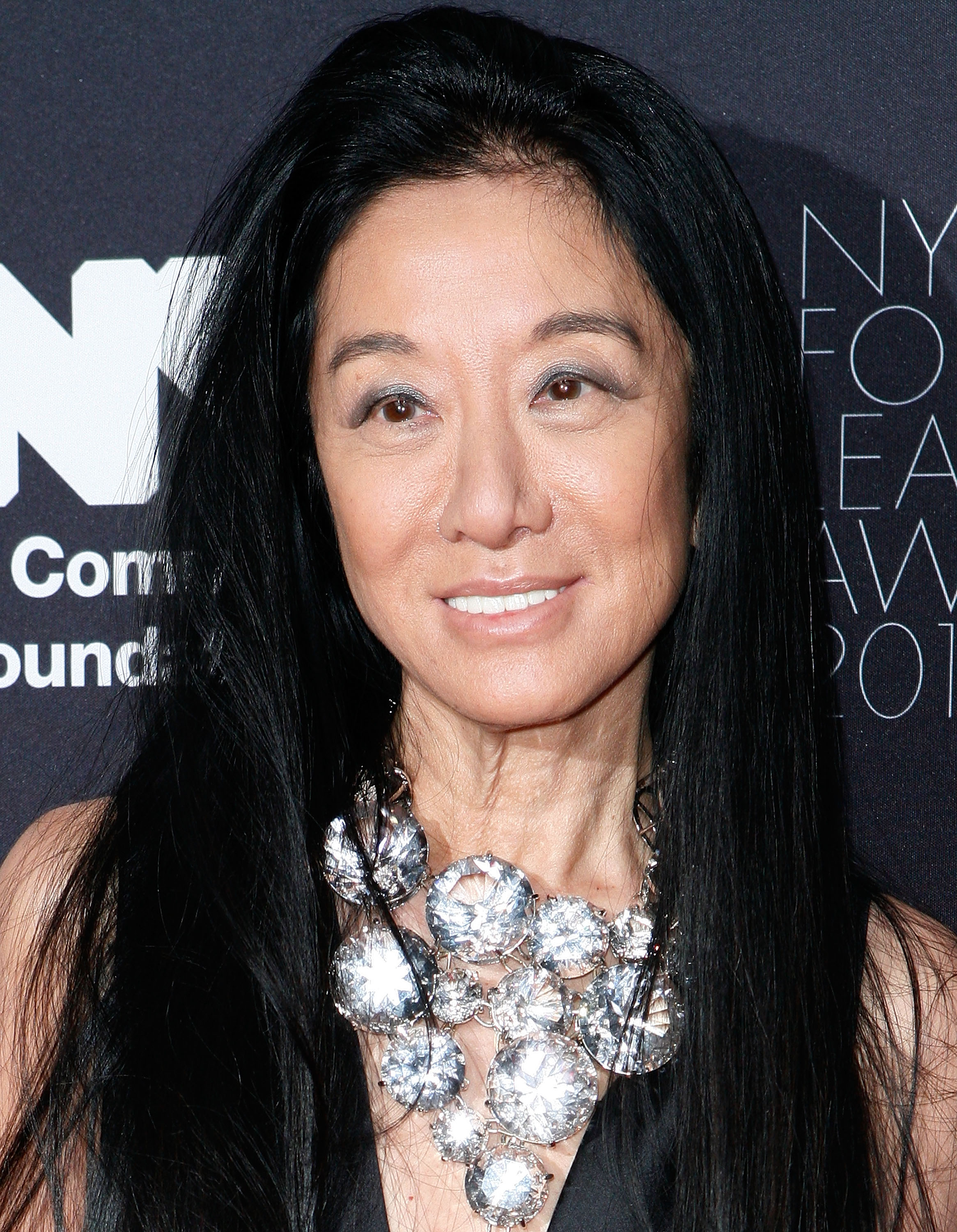Vera Wang erschien mit einem strahlenden Lächeln bei der Gala der NYC & Company Foundation Leadership Awards, die am 1. Dezember 2010 im Plaza Hotel in New York City stattfand. Die gefeierte Designerin setzte mit einer opulenten Halskette, bestehend aus übergroßen, facettenreichen Kristallscheiben, Akzente zu ihrem schwarzen Abendoutfit. Diese umrahmte ihre Gesichtszüge unter voluminösem, wallendem schwarzem Haar und schimmerndem silbernem Augen-Make-up. | Quelle: Getty Images