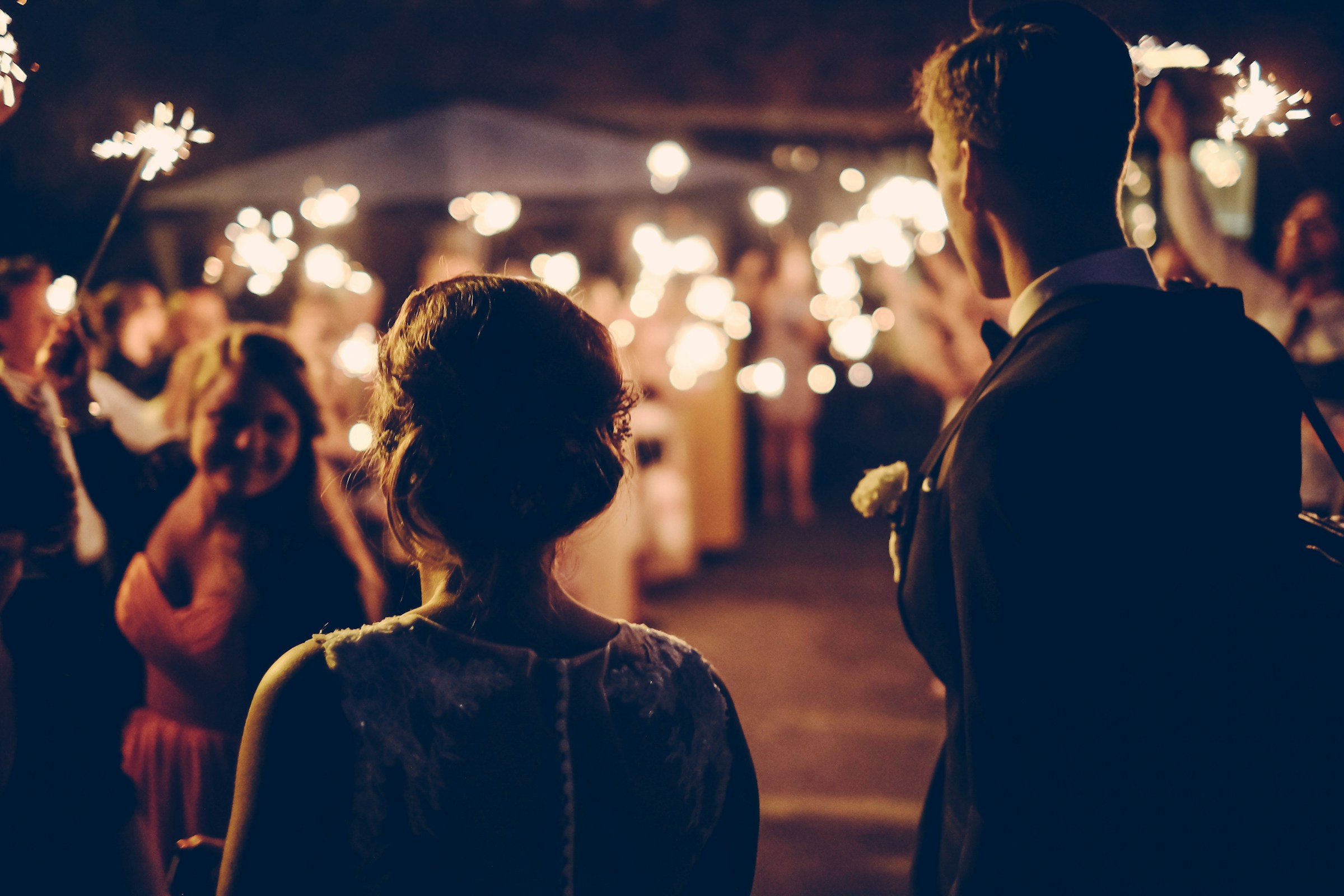 Rückansicht eines frisch verheirateten Paares bei der Afterparty ihrer Hochzeit | Quelle: Unsplash