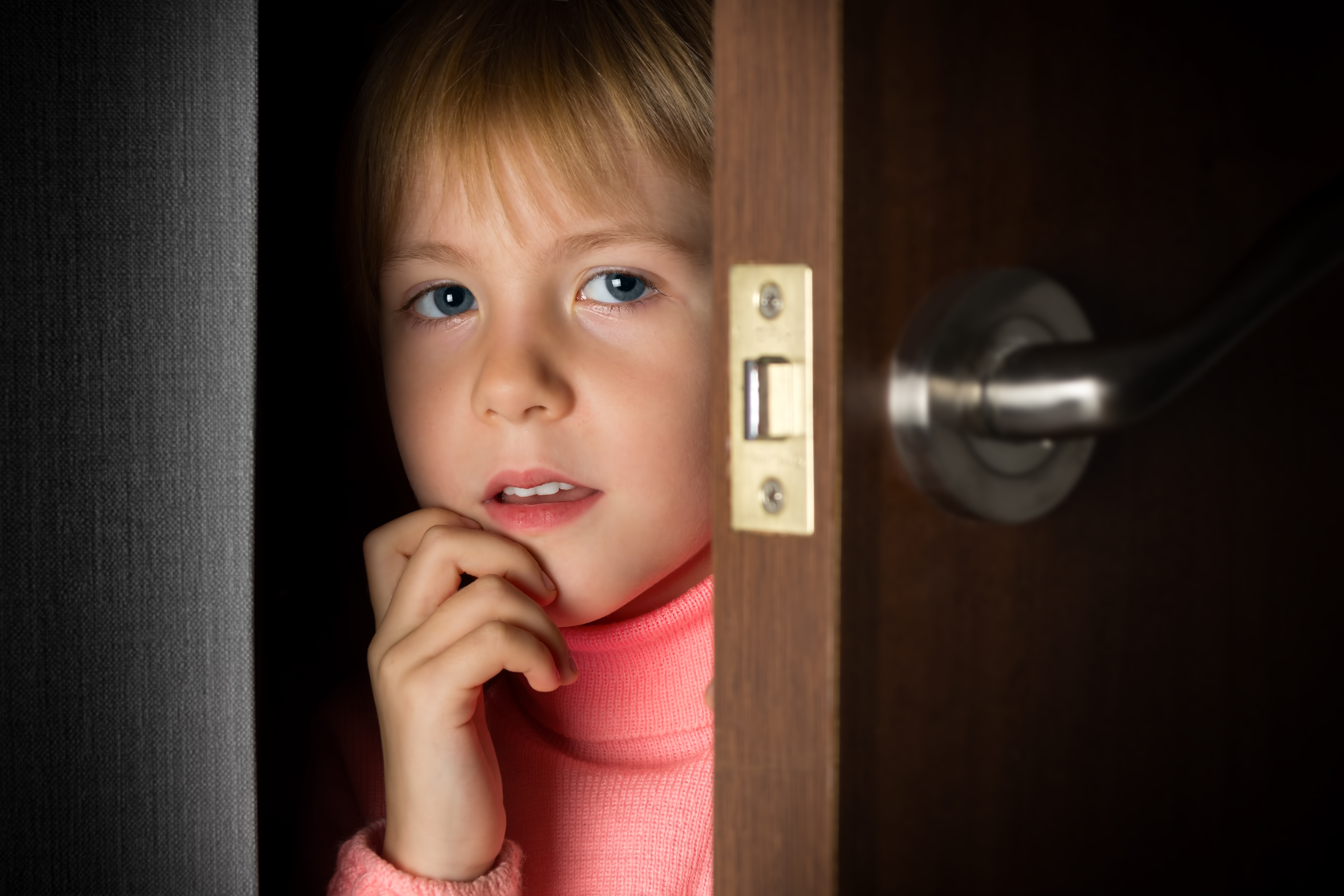 Ein kleines Mädchen späht durch eine Tür | Quelle: Shutterstock