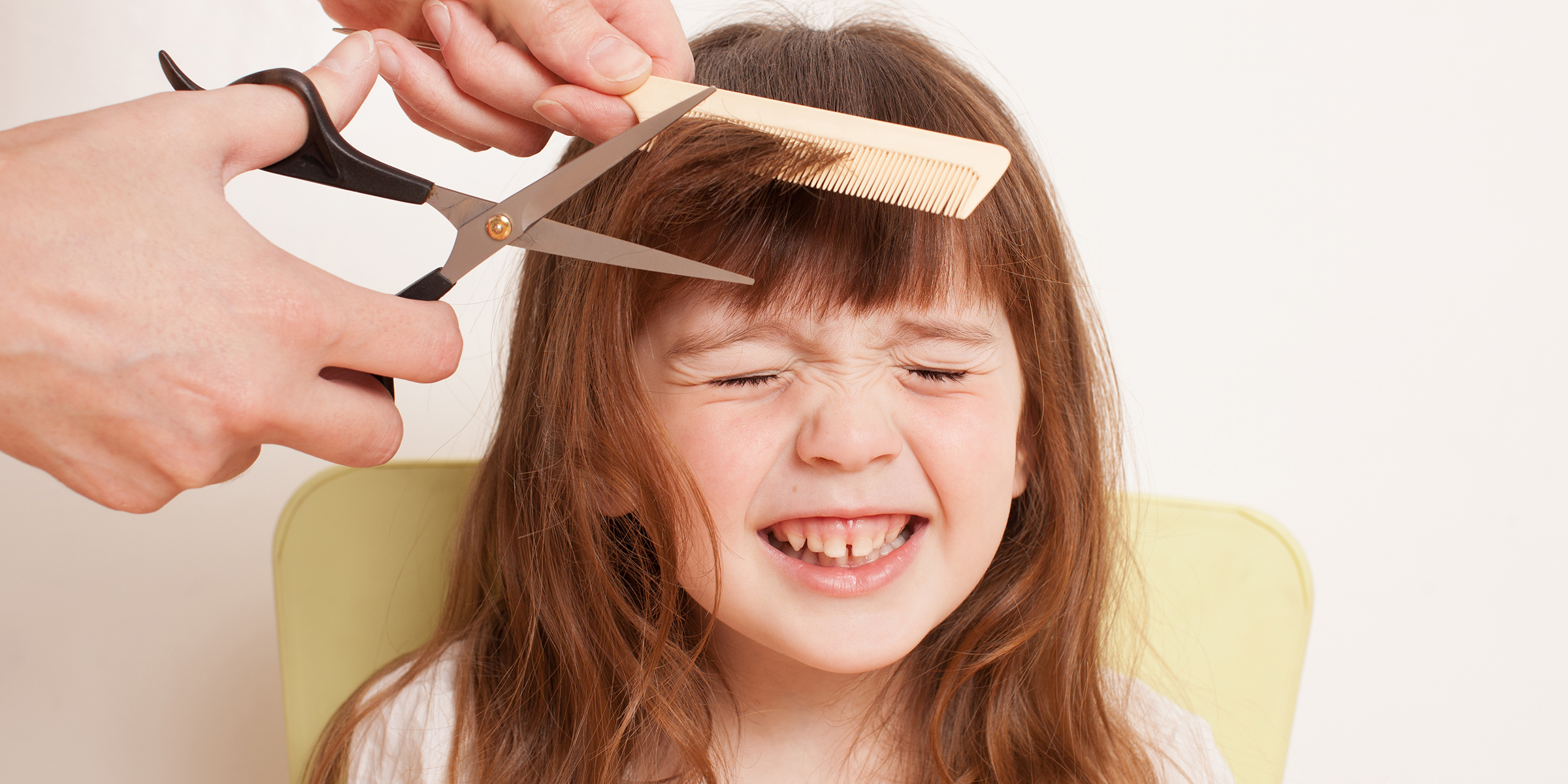 Eine Person, die einem kleinen Mädchen die Haare schneidet | Quelle: Shutterstock