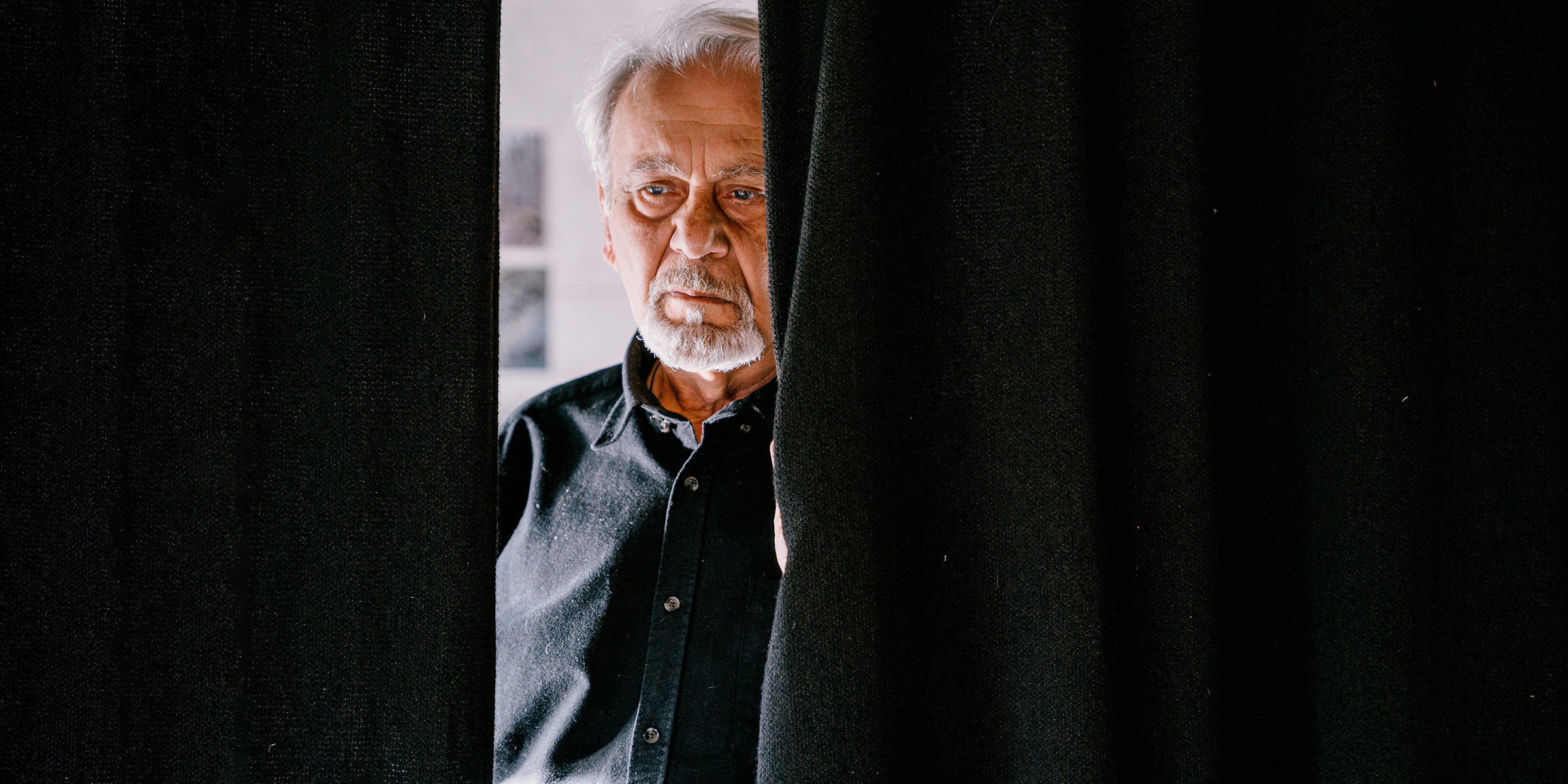 Trauriger Mann, der hinter dem Vorhang steht | Quelle: Pexels
