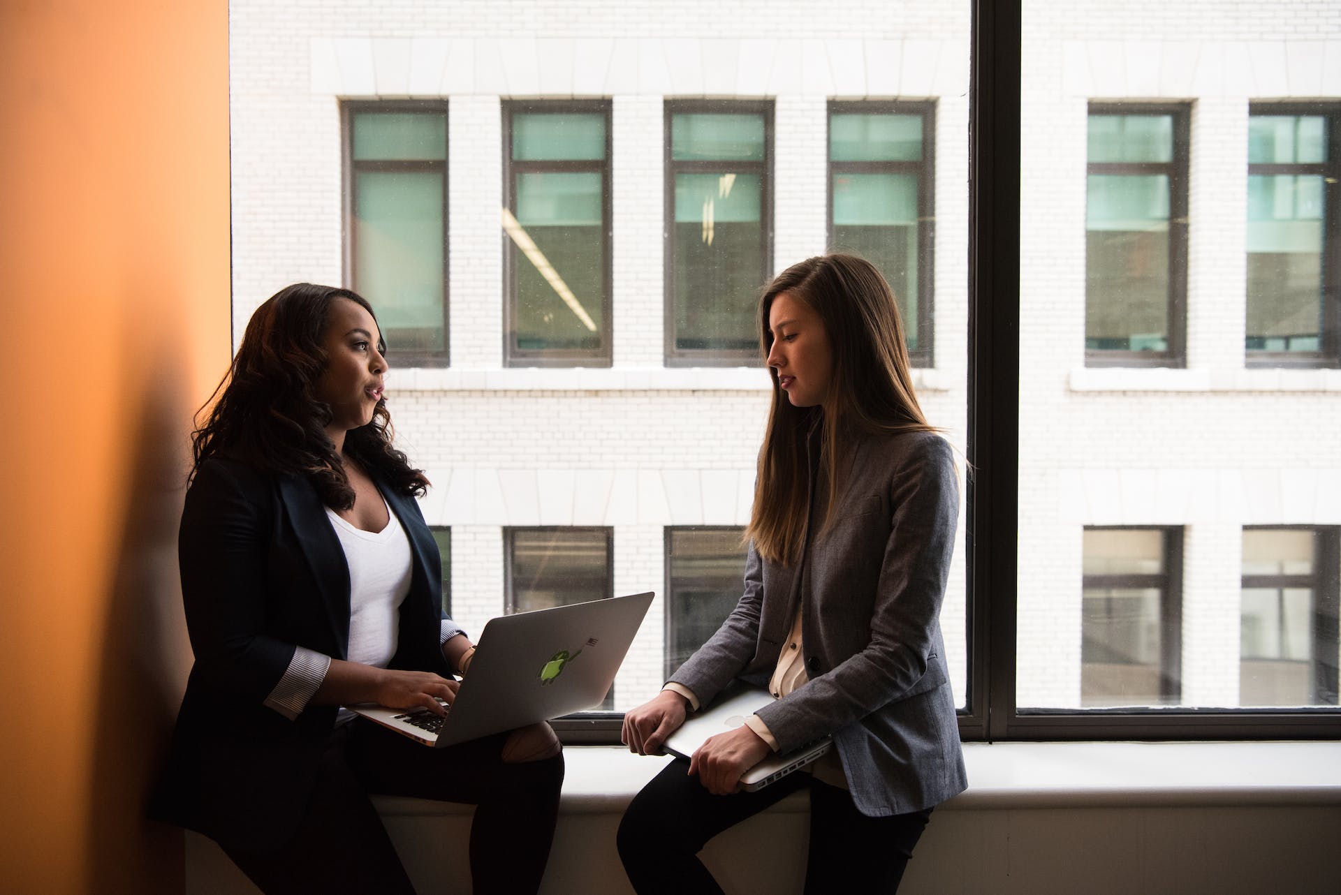 Zwei Frauen unterhalten sich an ihrem Arbeitsplatz | Quelle: Pexels