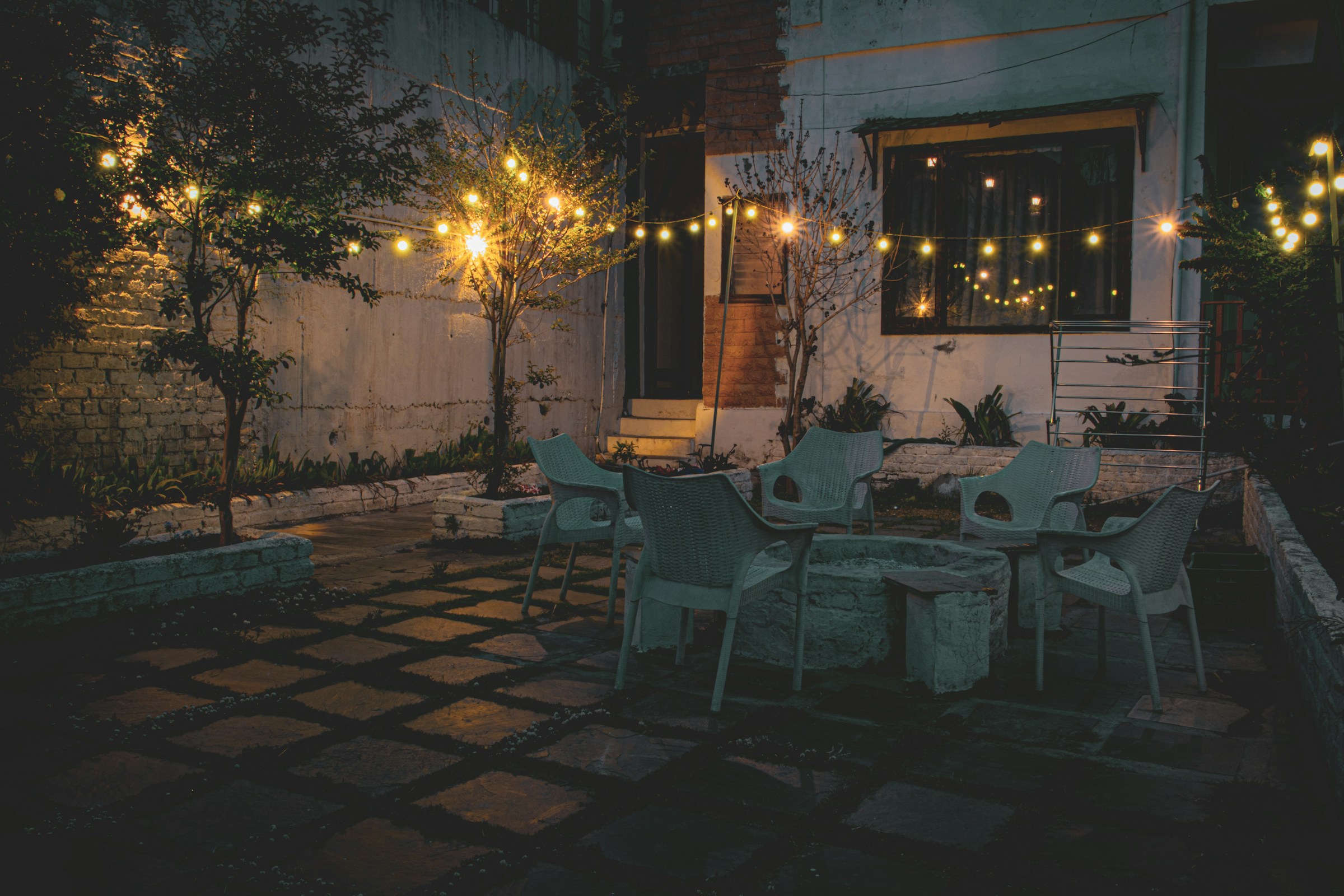 Ein entfernter Blick auf eine Terrasse mit gelben Lichtern, Tischen und Stühlen | Quelle: Unsplash