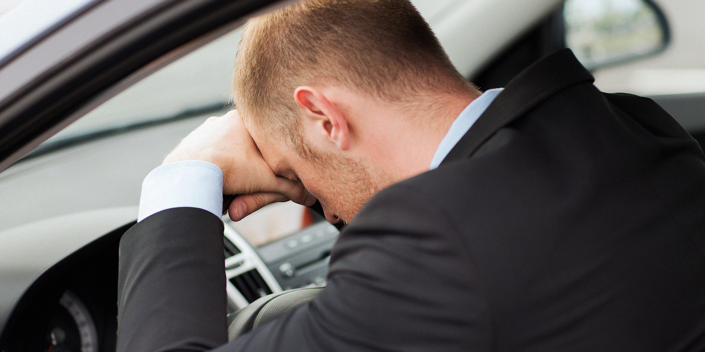 Mann im Auto sitzend mit dem Kopf auf dem Lenkrad | Quelle: Shutterstock