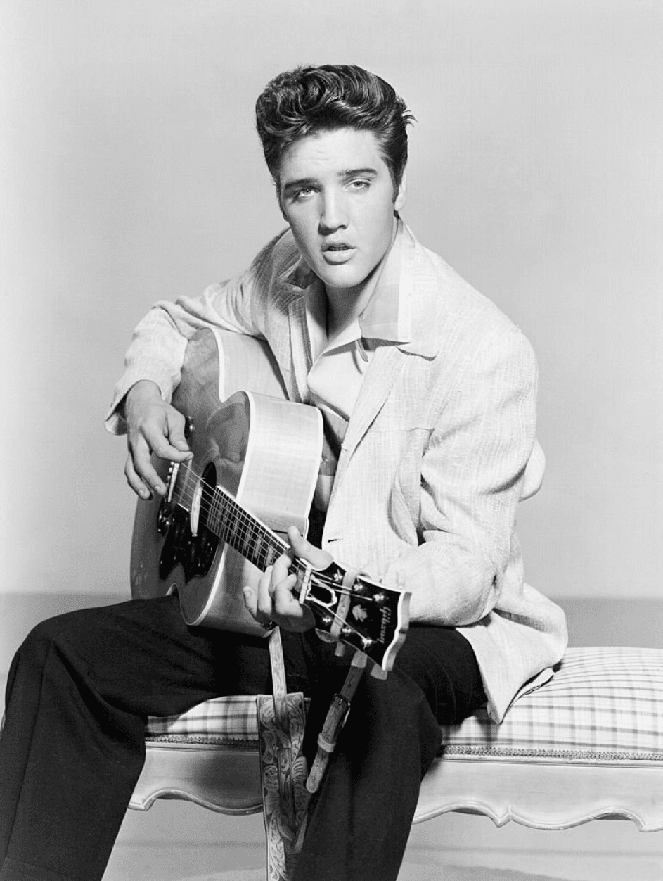 Elvis Presley stimmt seine akustische Gitarre in einem 1956 Portrait. | Quelle: Getty Images