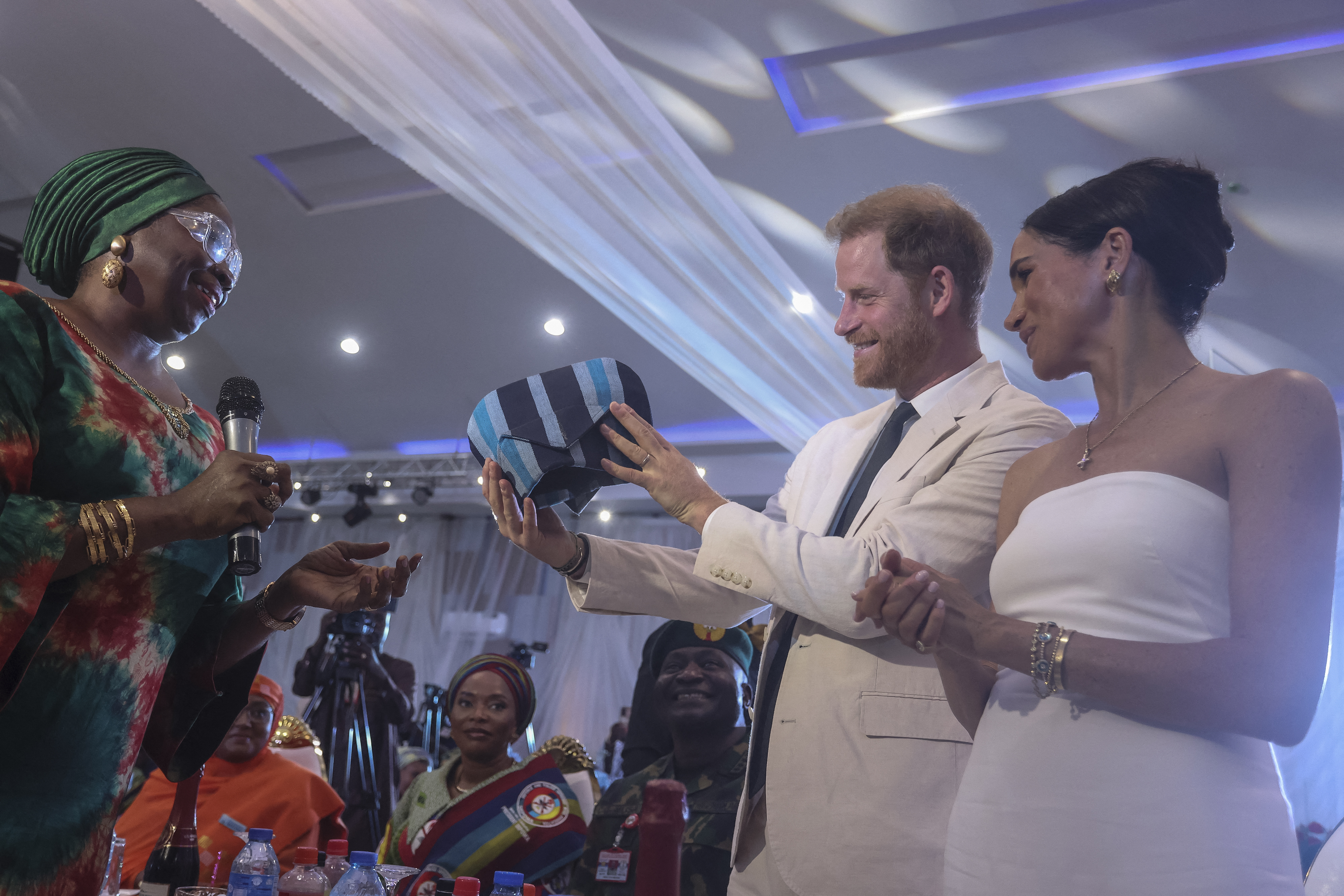 Prinz Harry und Meghan Markle erhalten ein traditionelles Outfit, als sie am 11. Mai 2024 an einem Sit Out im nigerianischen Verteidigungshauptquartier in Abuja teilnehmen. | Quelle: Getty Images