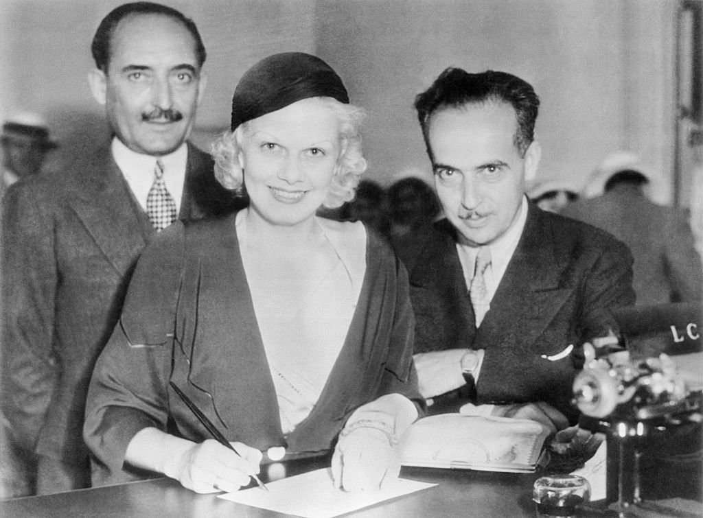 Jean Harlow, der platinblonde Filmstar, mit Paul Bern, beim Unterschreiben der Hochzeitspapiere, in Beverly Hills, am 2. Juli 1932. | Quelle: Getty Images