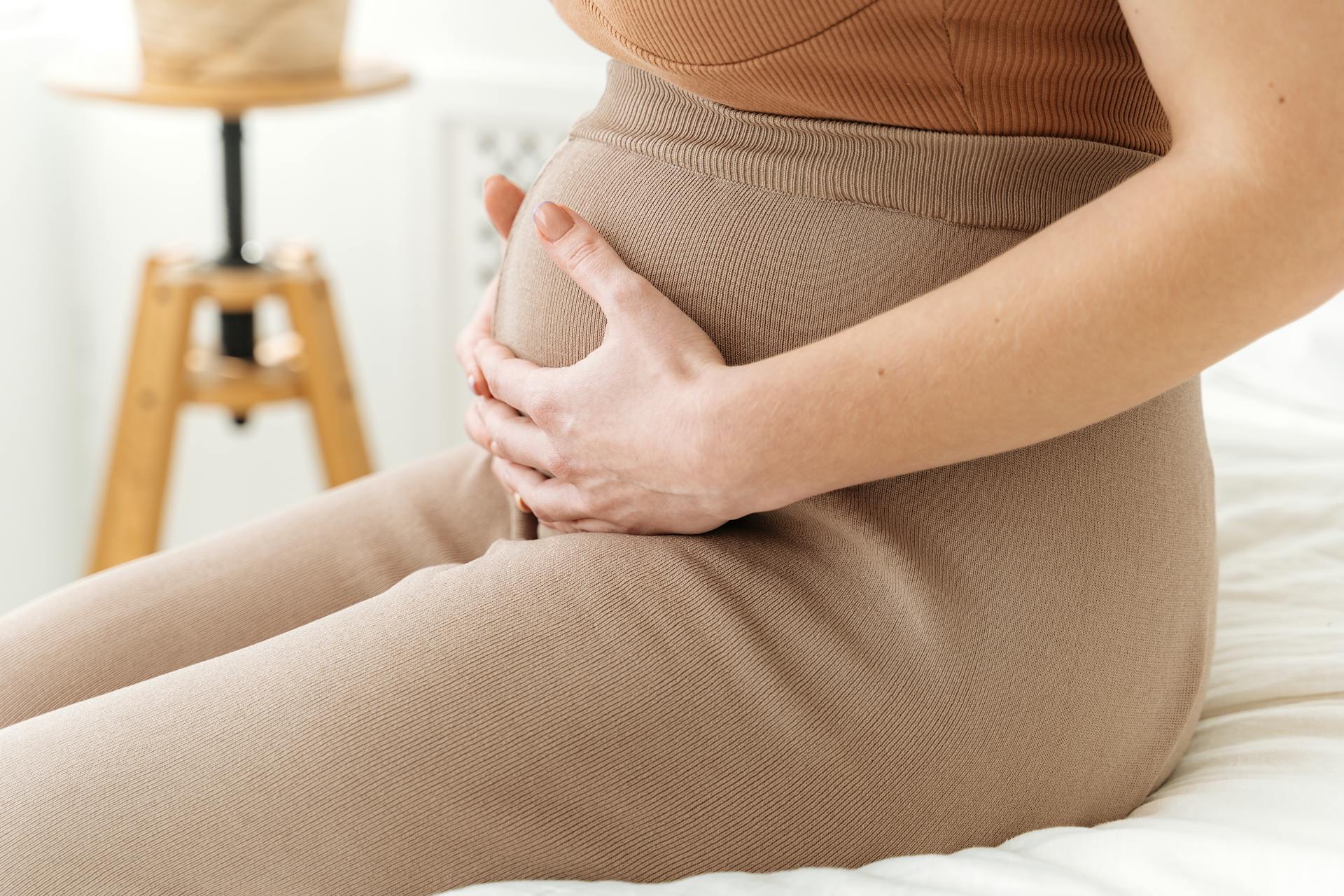 Eine Frau sitzt mit ihren Händen auf ihrem Babybauch | Quelle: Pexels