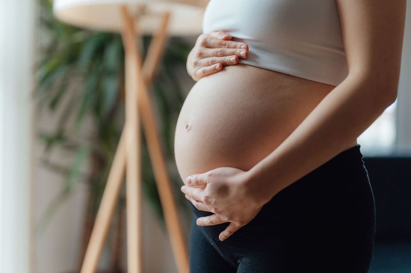 Eine schwangere Frau zeigt ihren Bauch. | Quelle: Getty Images