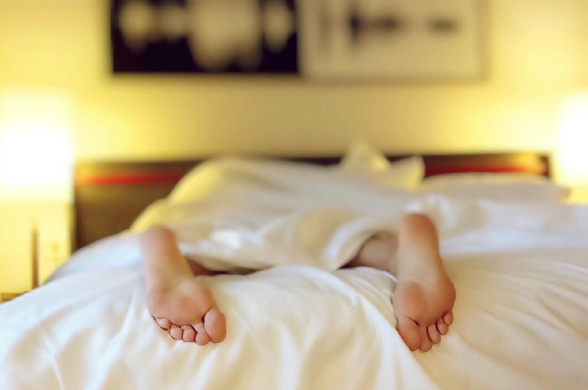 Eine Person liegt mit dem Gesicht nach unten auf einem Bett | Quelle: Pexels