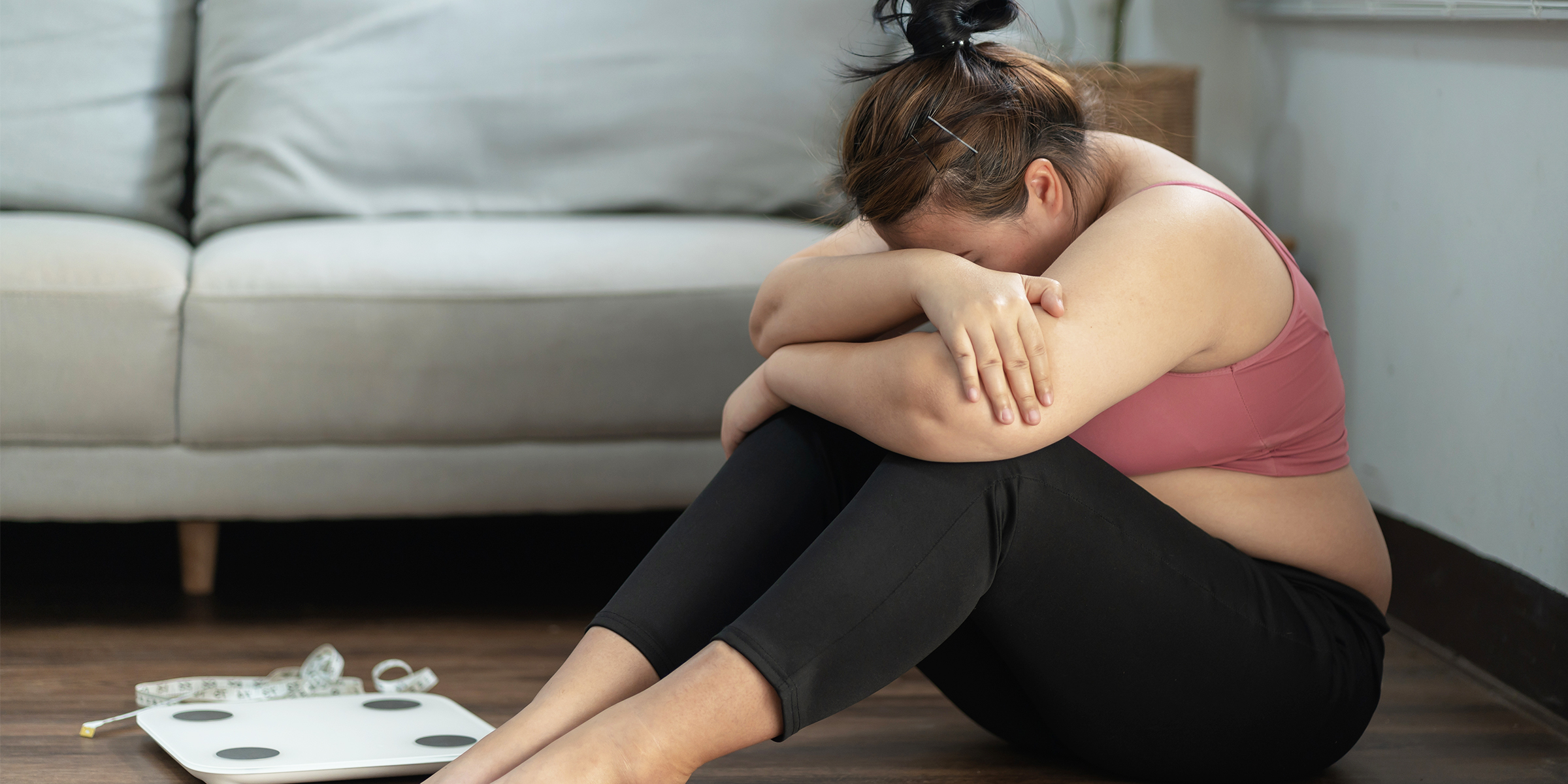 Eine weinende Frau, die neben einer Waage sitzt | Quelle: Shutterstock