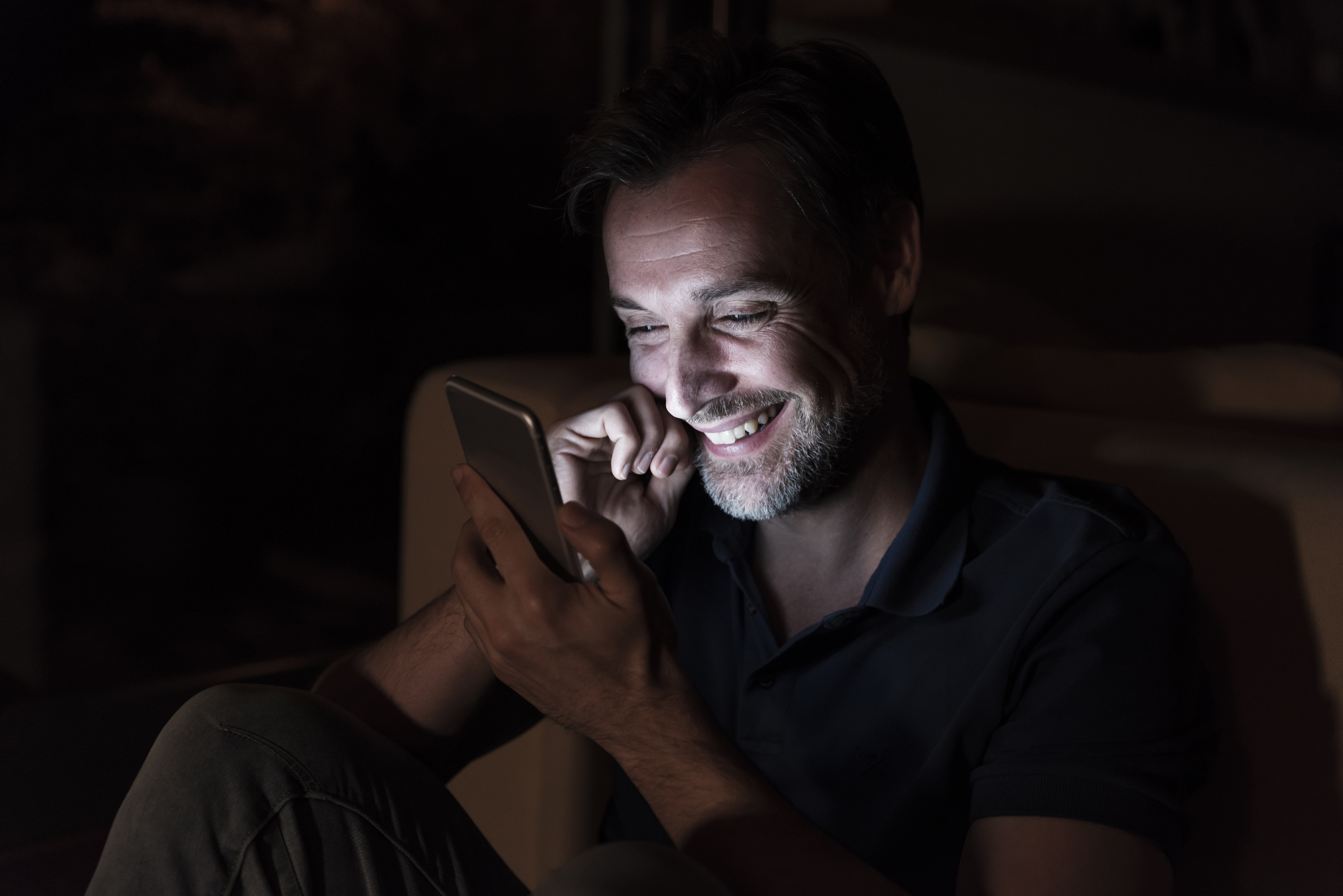 Mann lachend beim SMS schreiben | Quelle: Getty Images