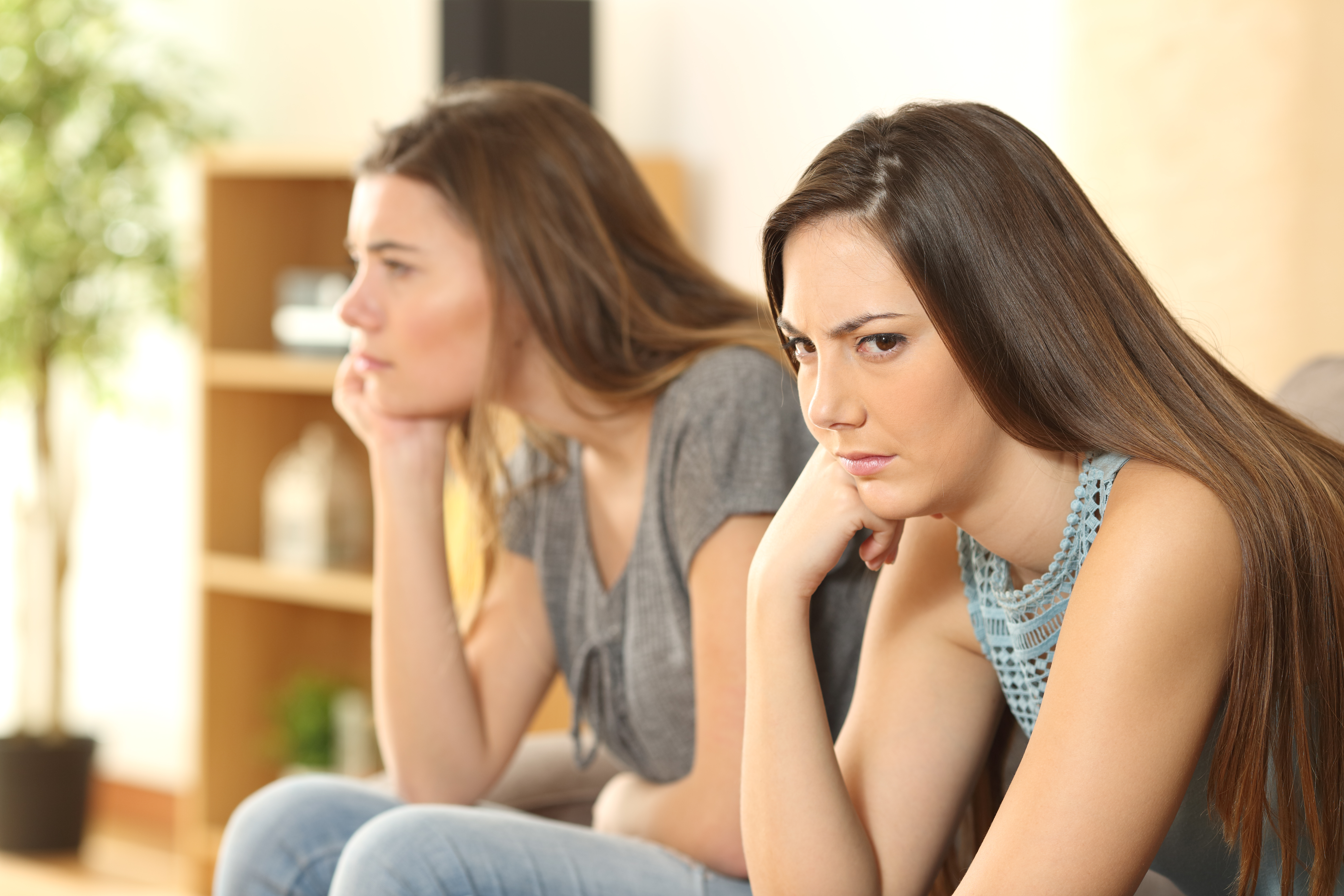 Zwei Schwestern sitzen auf einem Sofa und reden nicht miteinander | Quelle: Shutterstock