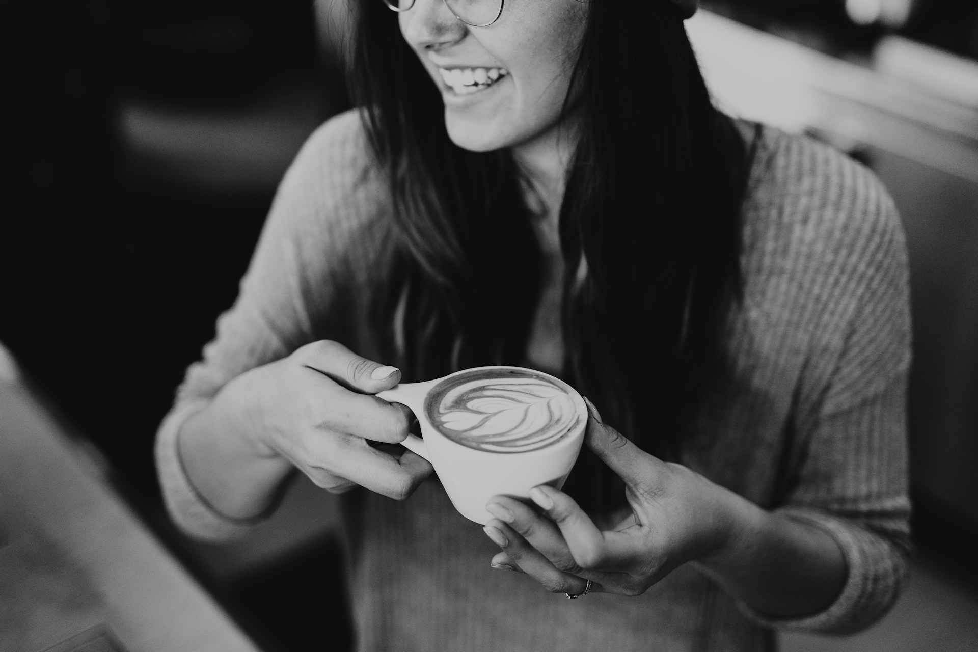 Eine Frau lacht, während sie eine Tasse Kaffee in der Hand hält | Quelle: Unsplash