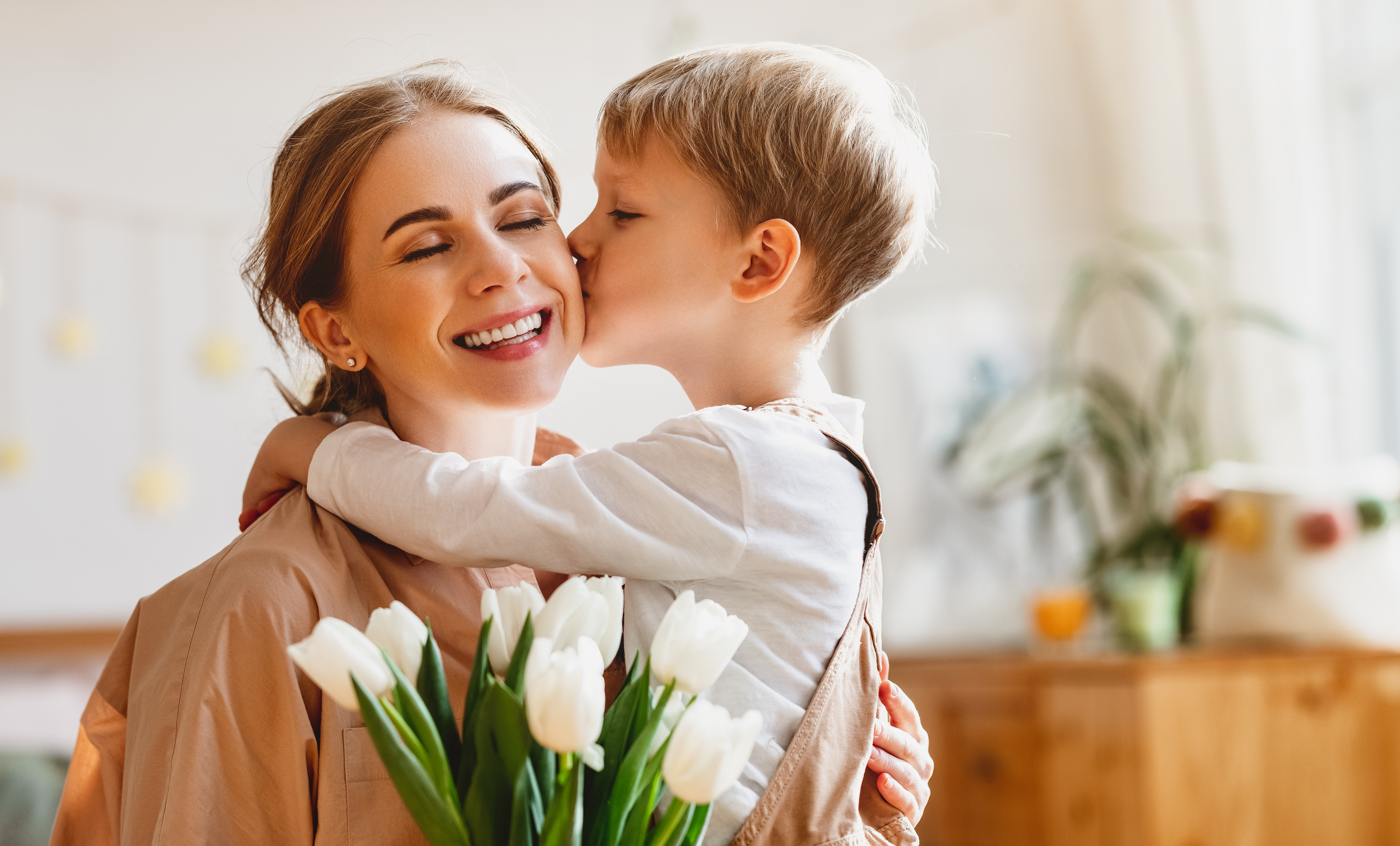Kleiner Junge küsst seine Mutter und schenkt ihr Blumen | Quelle: Shutterstock