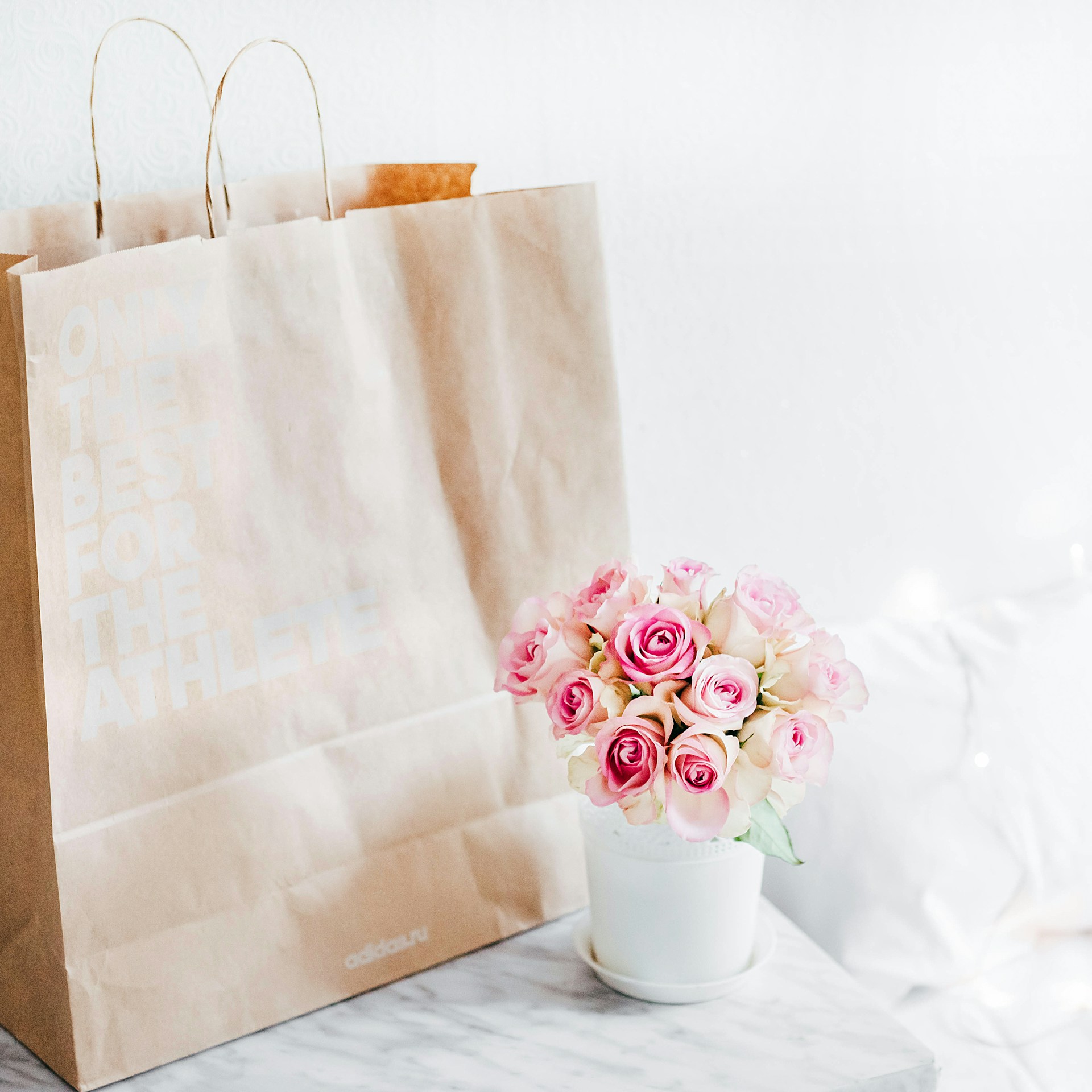 Eine Papiertüte neben einer Vase mit Rosen | Quelle: Unsplash