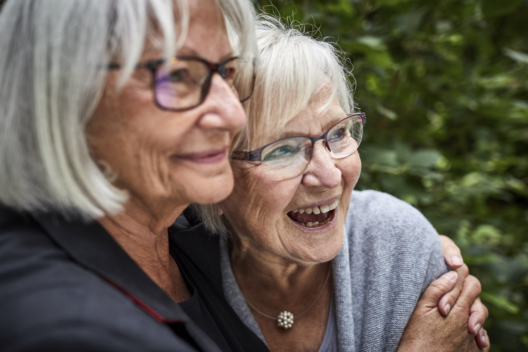 Zwei ältere Frauen umarmen sich im Garten. I Quelle: Getty Images