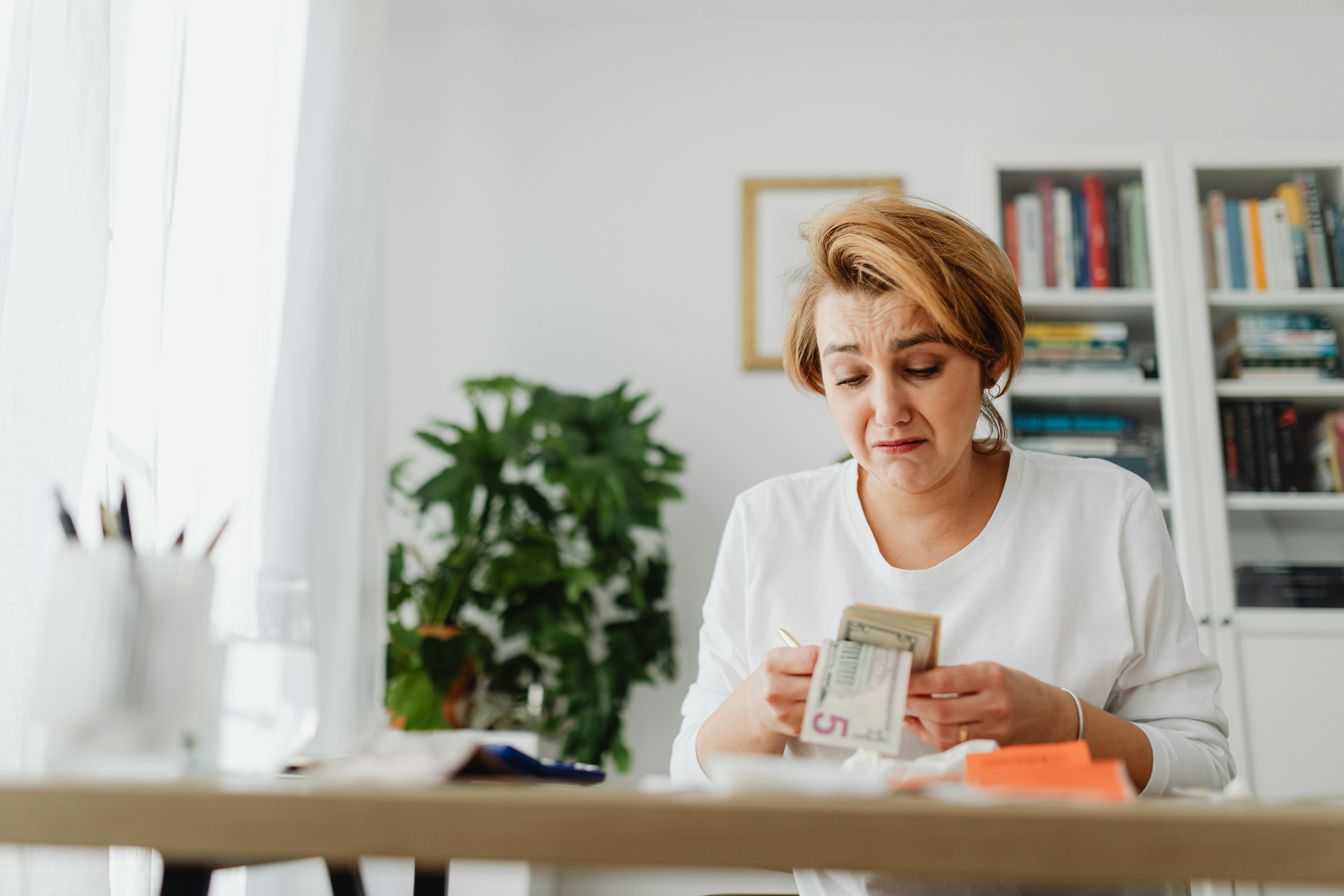 Eine traurige Frau beim Geldzählen | Quelle: Pexels