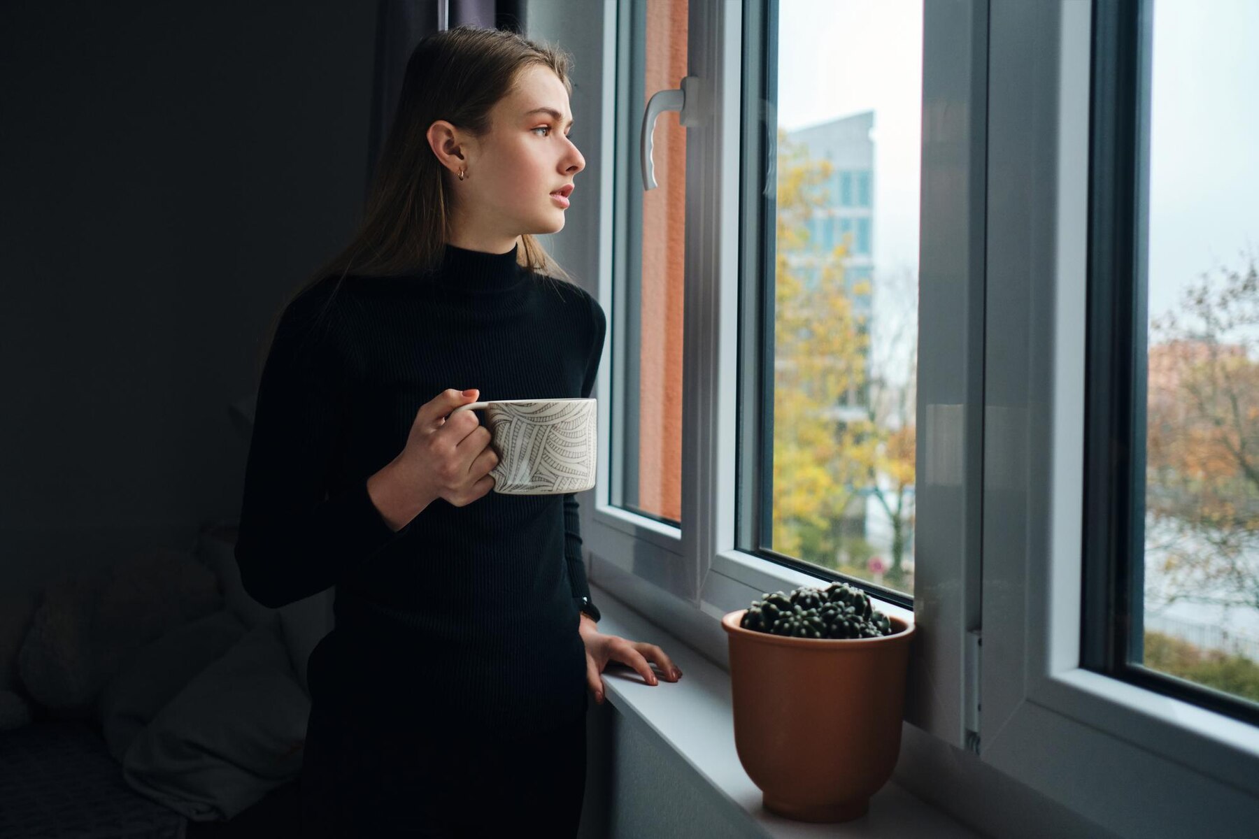 Eine besorgte Frau schaut aus dem Fenster | Quelle: Freepik