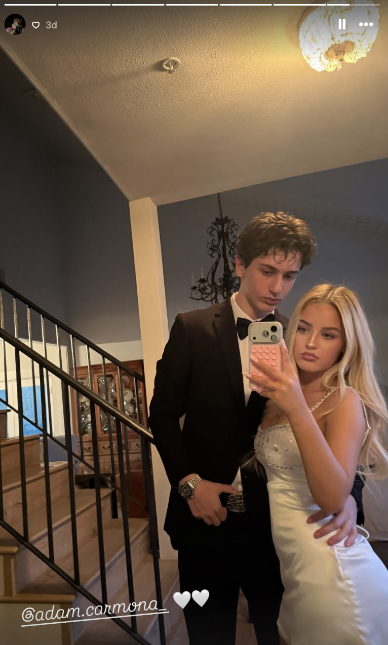 Finley Lockwood posiert für ein Spiegel-Selfie auf der Treppe zusammen mit ihrem Date Adam Carmona. Sie trägt ein verziertes, trägerloses Minikleid aus weißem Satin mit funkelnden Kristallakzenten am Ausschnitt, während er einen klassischen schwarzen Smoking und eine Fliege trägt. | Quelle: Instagram/finleyl.ockwood
