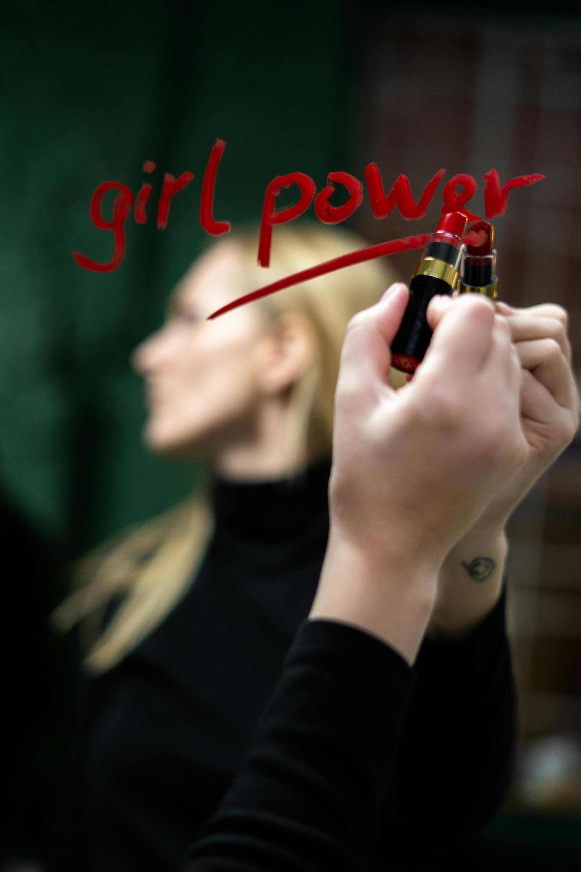 Eine Frau, die mit rotem Lippenstift auf einen Spiegel schreibt | Quelle: Pexels