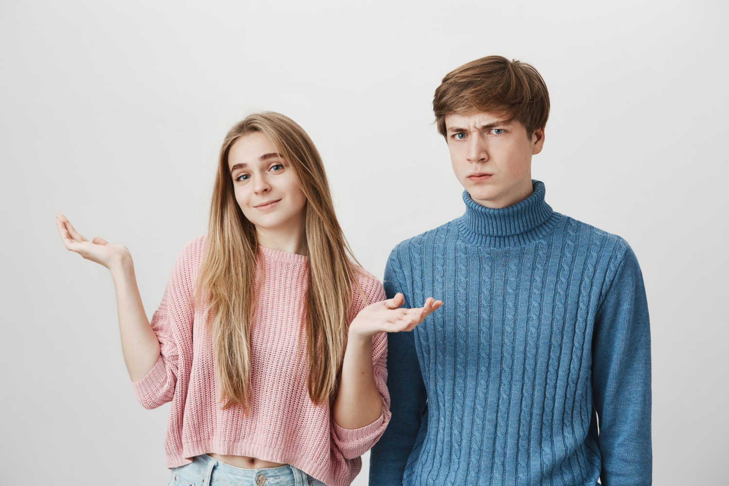 Ein junges Mädchen zuckt neben einem genervten Teenager mit den Schultern | Quelle: Freepik