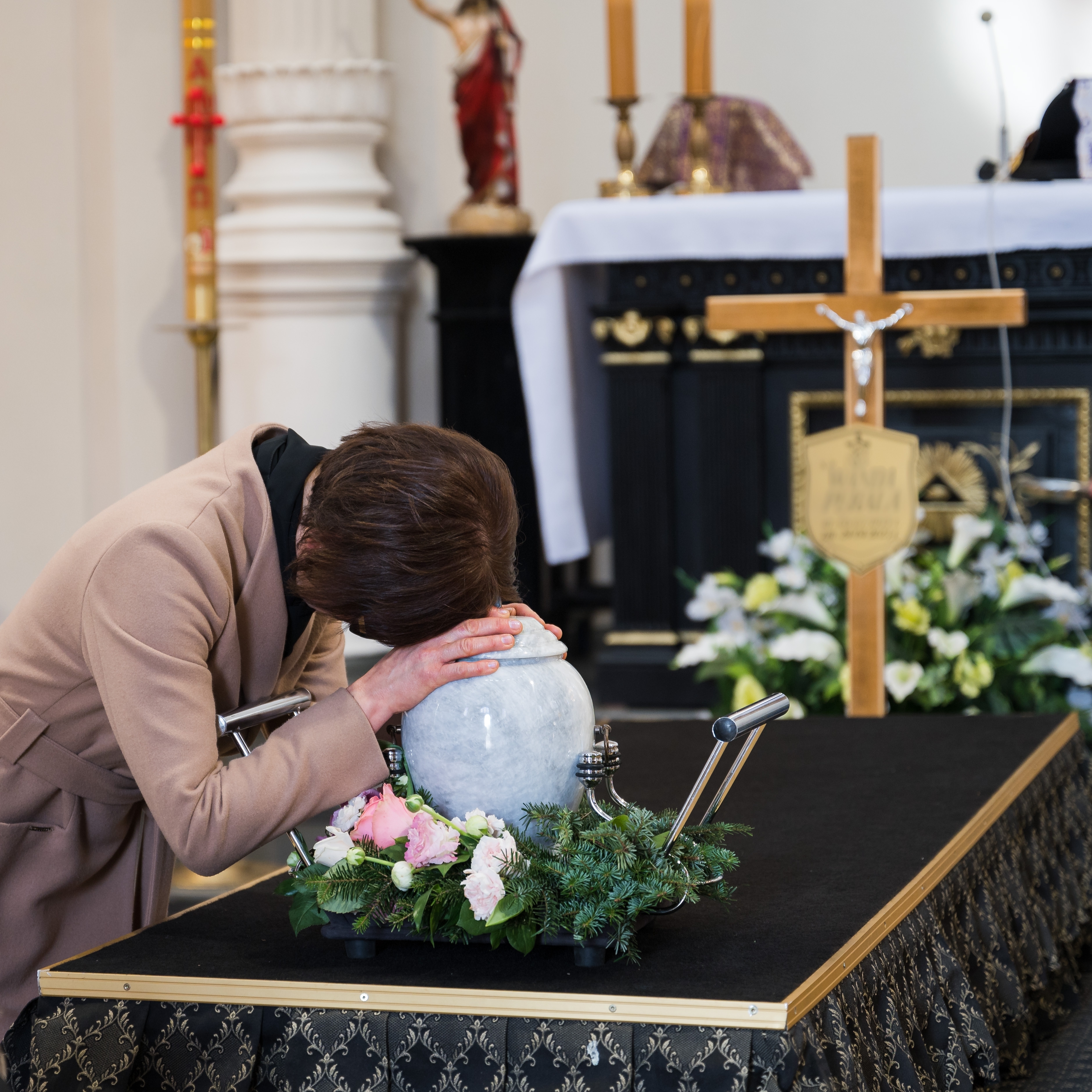 Eine Frau weint während einer Beerdigung über der Urne eines geliebten Menschen | Quelle: Shutterstock
