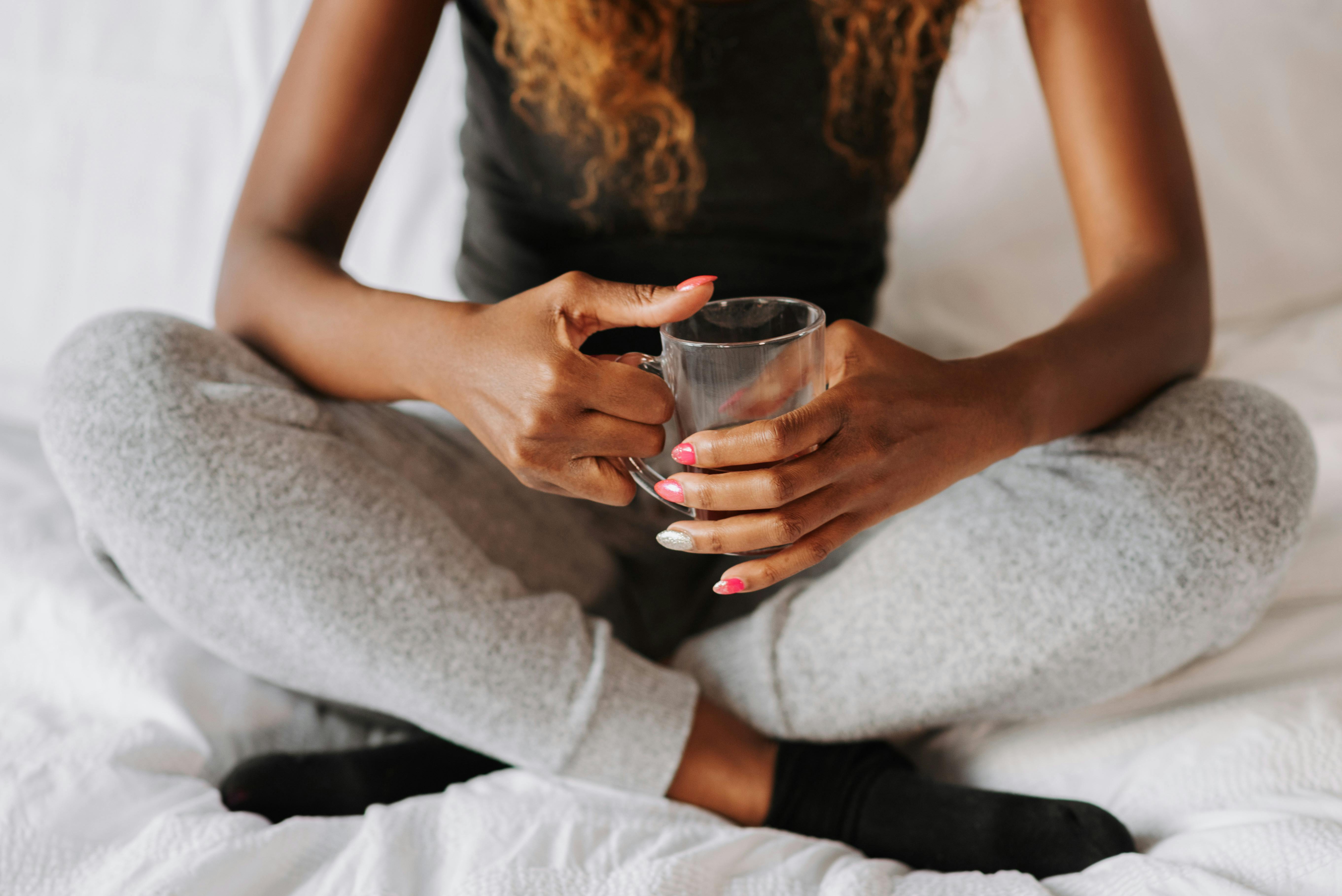 Eine Frau mit einer Tasse in ihrem Schlafzimmer | Quelle: Pexels