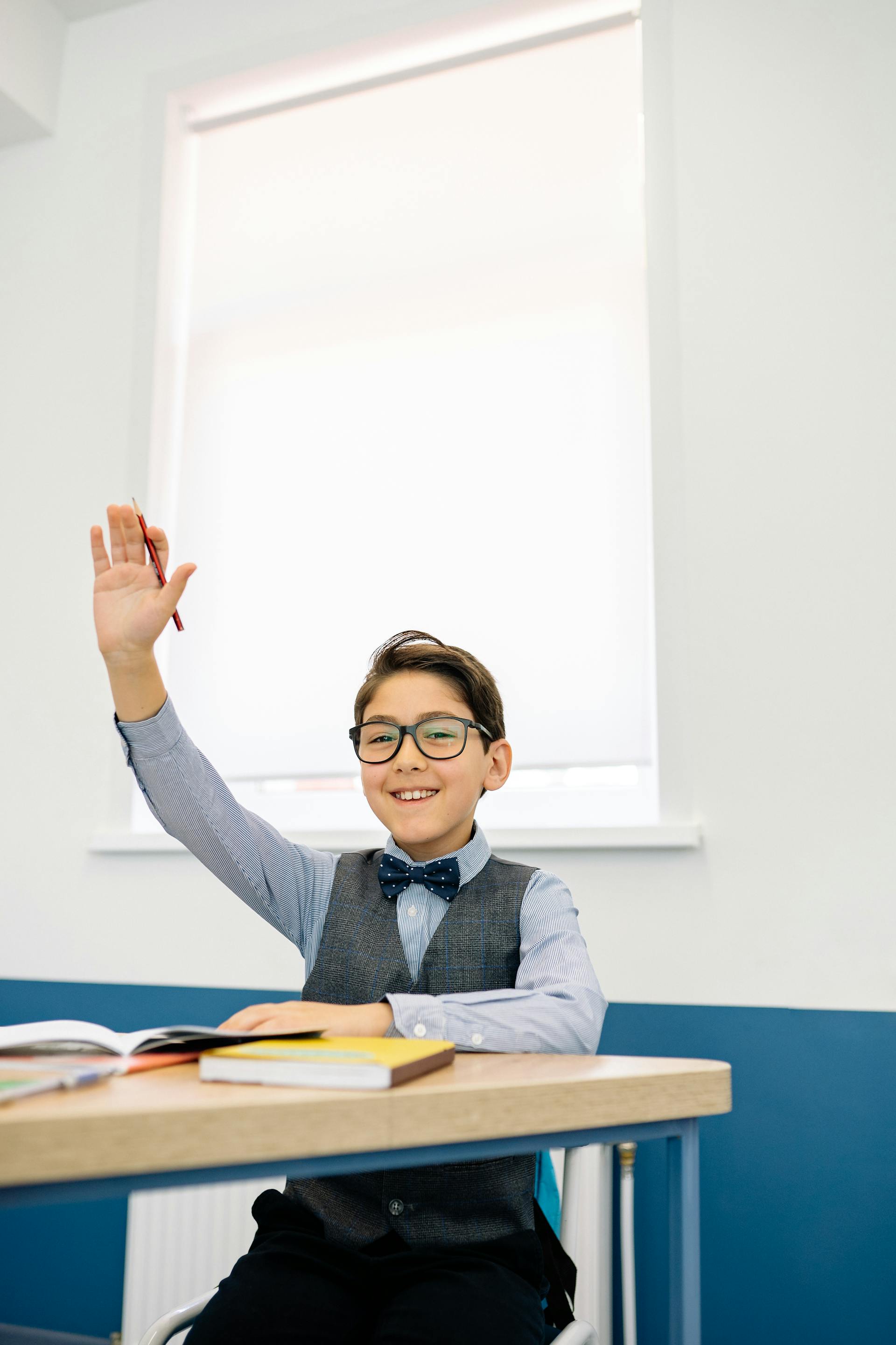 Ein kleiner Junge hebt seine Hand in einem Klassenzimmer | Quelle: Pexels