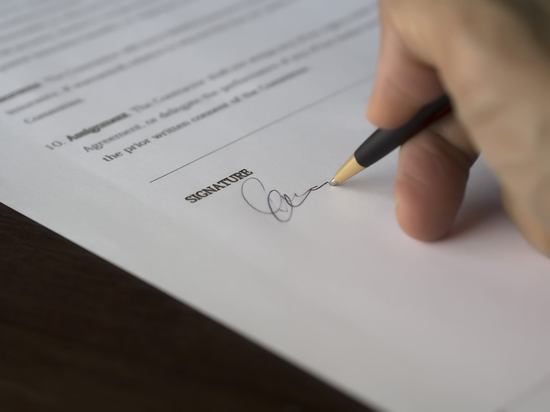 Person beim Unterschreiben von Papieren | Quelle: Pexels