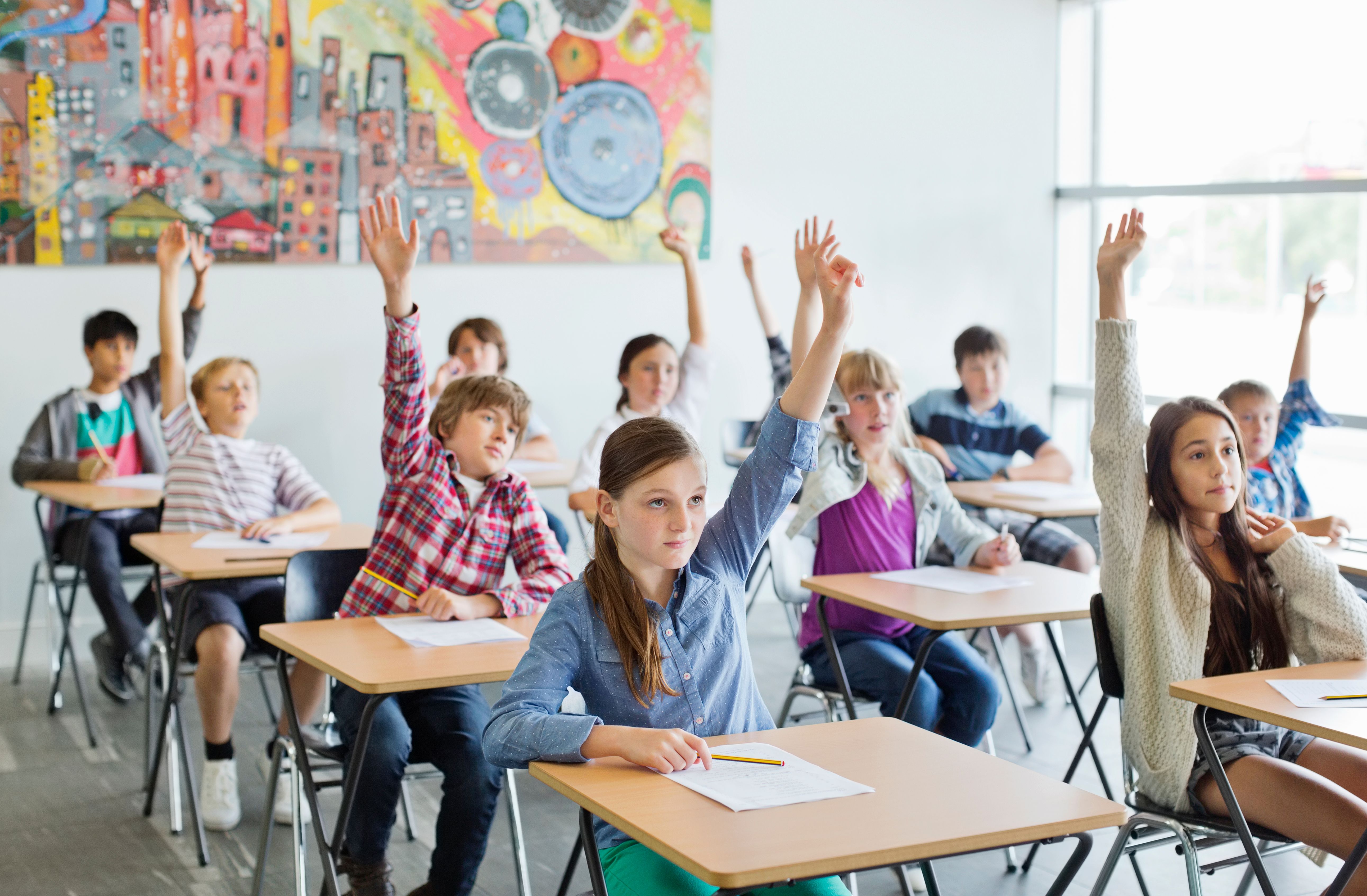 Schüler/innen heben im Unterricht die Hände. | Quelle: Getty Images