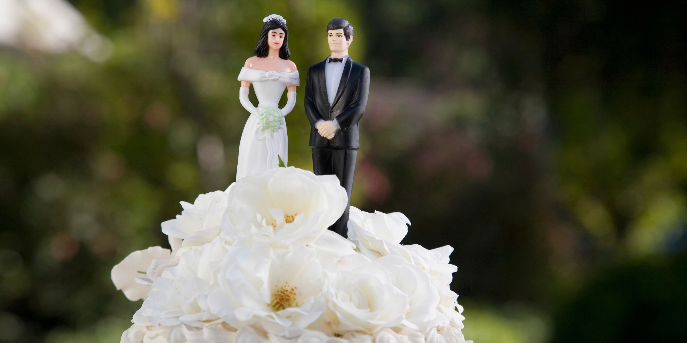 Nahaufnahme von Braut- und Bräutigam-Figuren auf einer Hochzeitstorte | Quelle: Getty Images