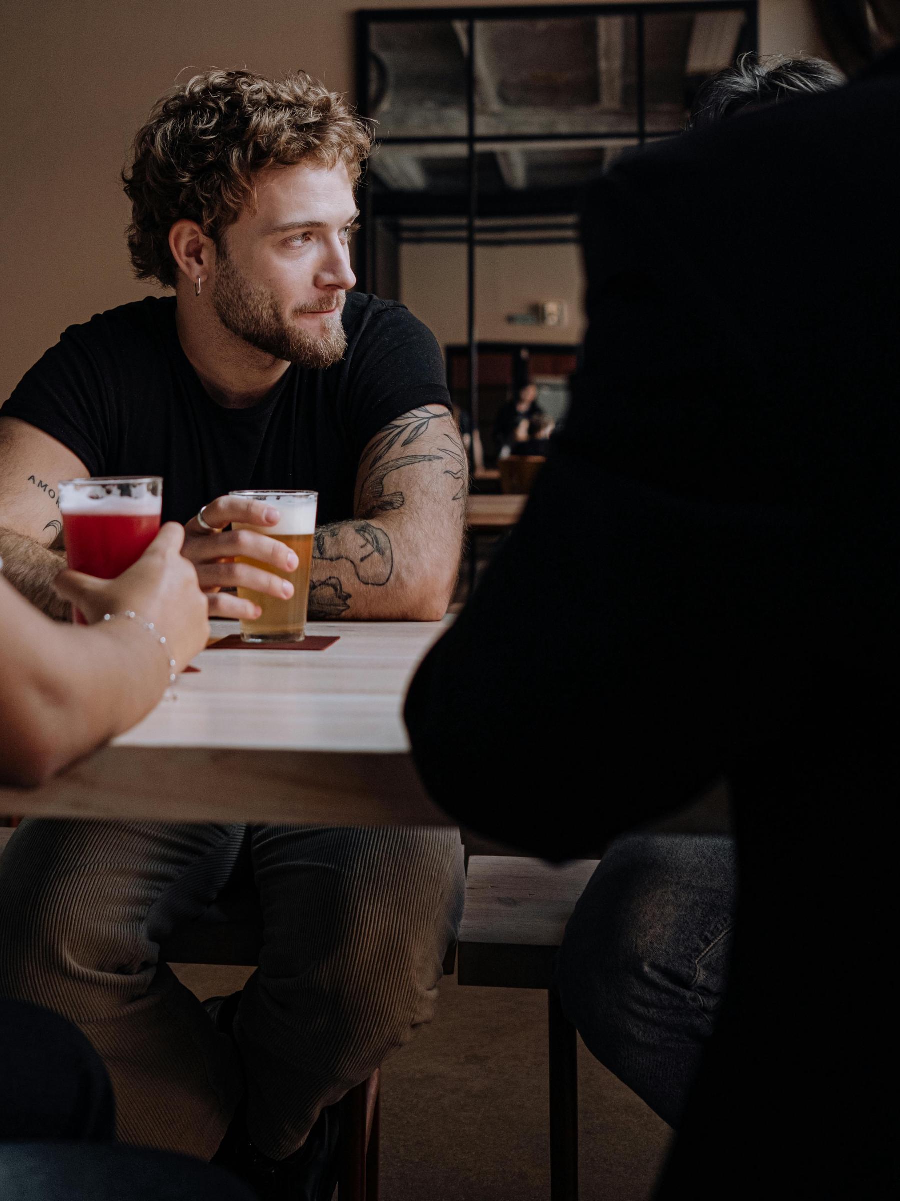 Ein Mann, der mit einem Bier in der Hand sitzend zur Seite schaut | Quelle: Pexels