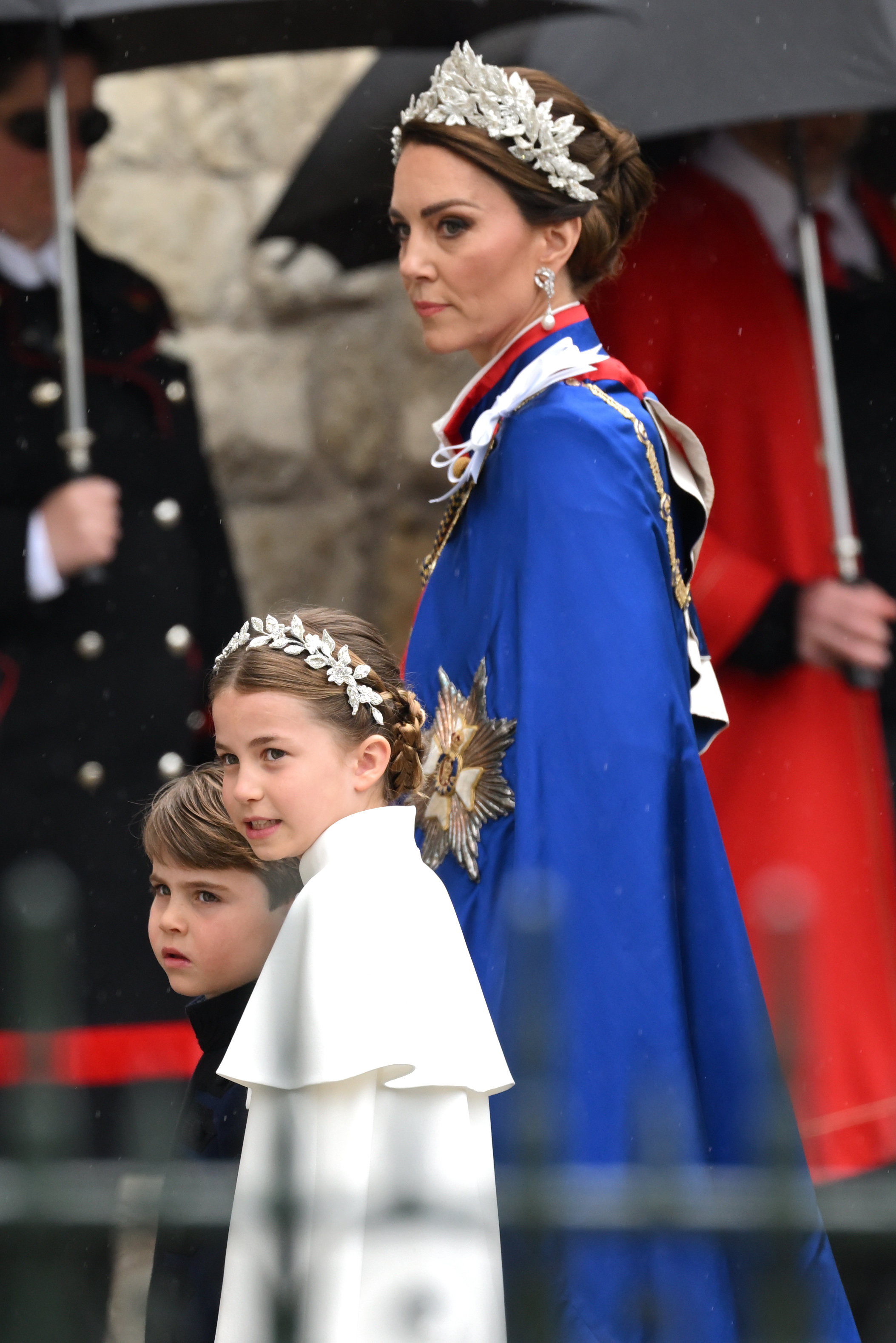 Prinzessin Charlotte trifft zusammen mit Prinz Louis und Catherine, Prinzessin von Wales, in der Westminster Abbey zur Krönung von König Charles III. und Königin Camilla am 6. Mai 2023 in London, England, ein. Charlotte sieht ihrer Mutter zum Verwechseln ähnlich in einem elfenbeinfarbenen Alexander-McQueen-Kleid mit einem Capelet und einem aufwendig gearbeiteten Kopfschmuck aus silbernen Goldfäden und Kristallblumen, während sie neben Prinz Louis in einer marineblauen Tunika von Dege & Skinner geht; Catherine steht derweil majestätisch da, gekleidet im Mantel des Royal Victorian Order und einem passenden floralen Kopfschmuck. | Quelle: Getty Images
