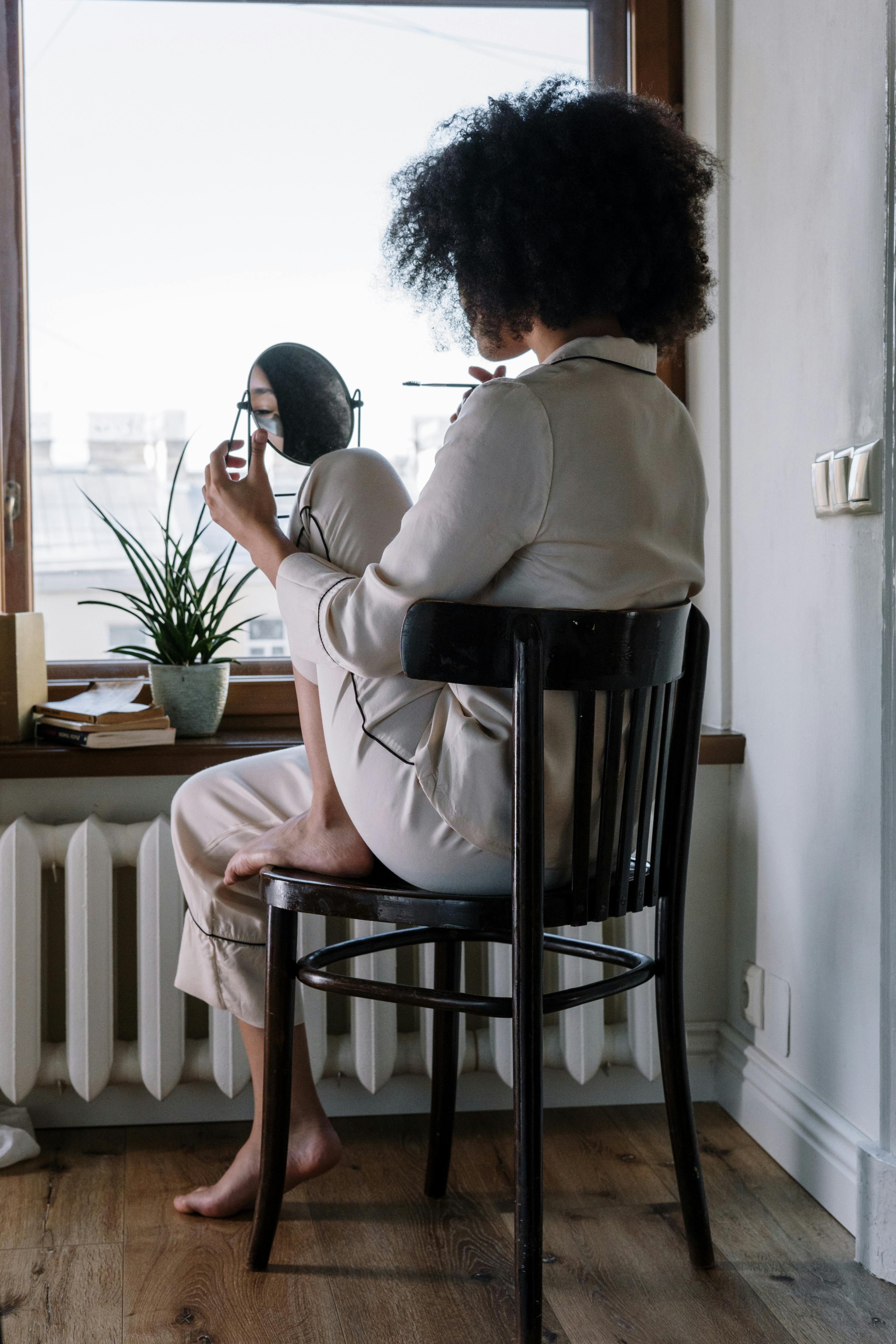 Eine Frau, die einen Schlafanzug trägt, während sie sich in einem Spiegel betrachtet | Quelle: Pexels