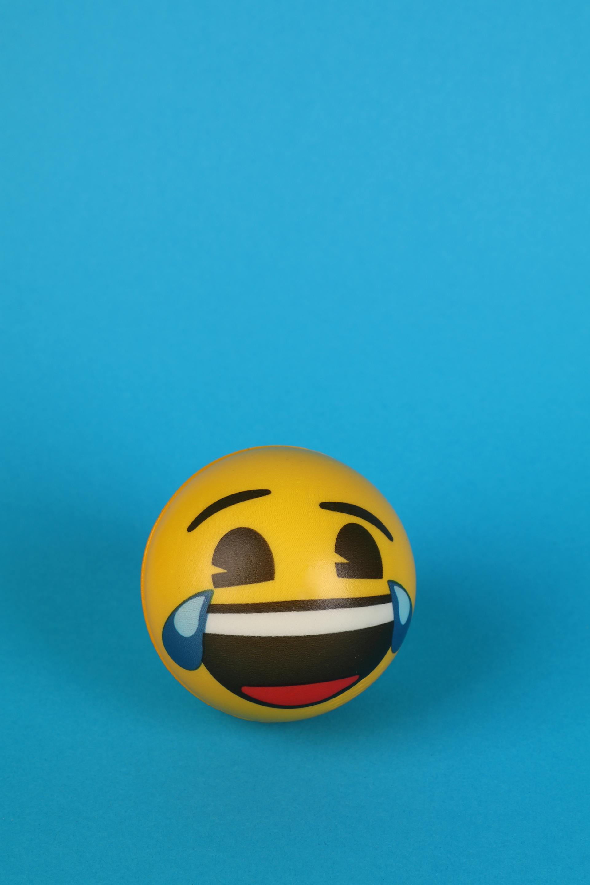 Ein lachendes Emoji mit Tränen in den Augen, gemalt auf einen gelben Ball | Quelle: Pexels