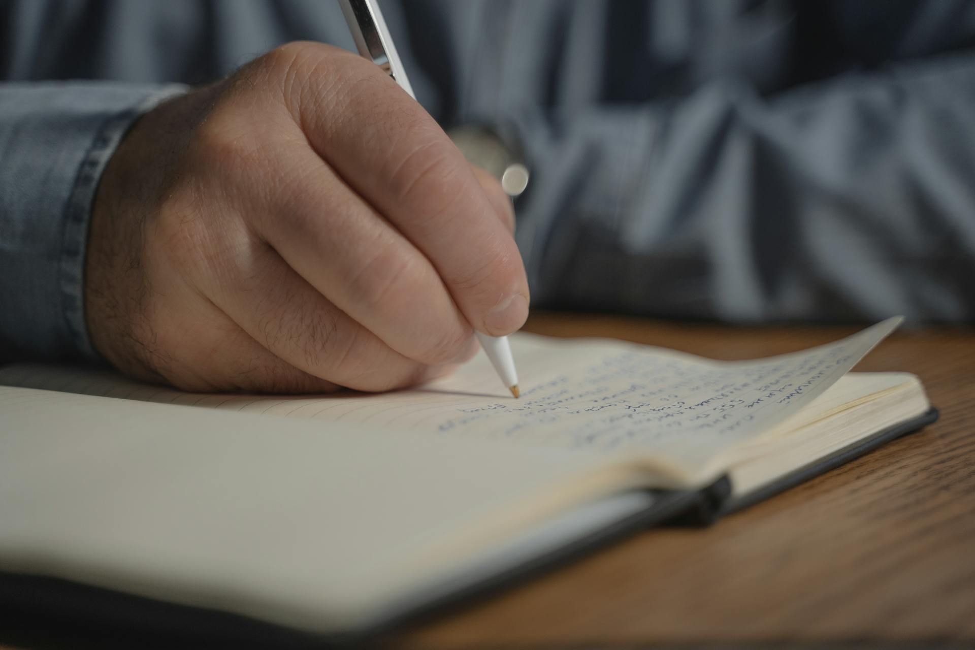 Ein Mann schreibt in sein Notizbuch | Quelle: Pexels