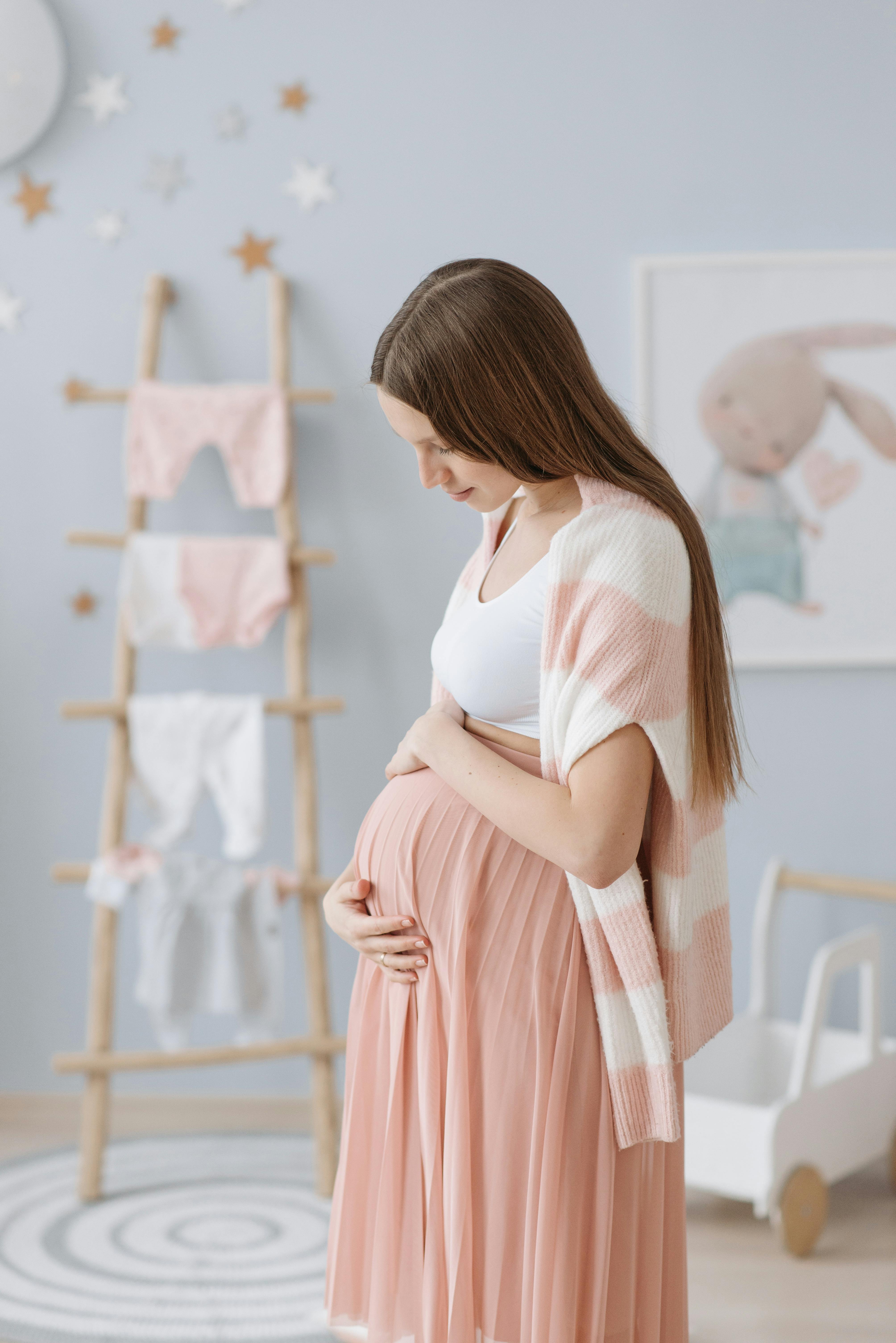 Eine schwangere Frau hält ihren Bauch im Zimmer ihres zukünftigen Babys | Quelle: Pexels