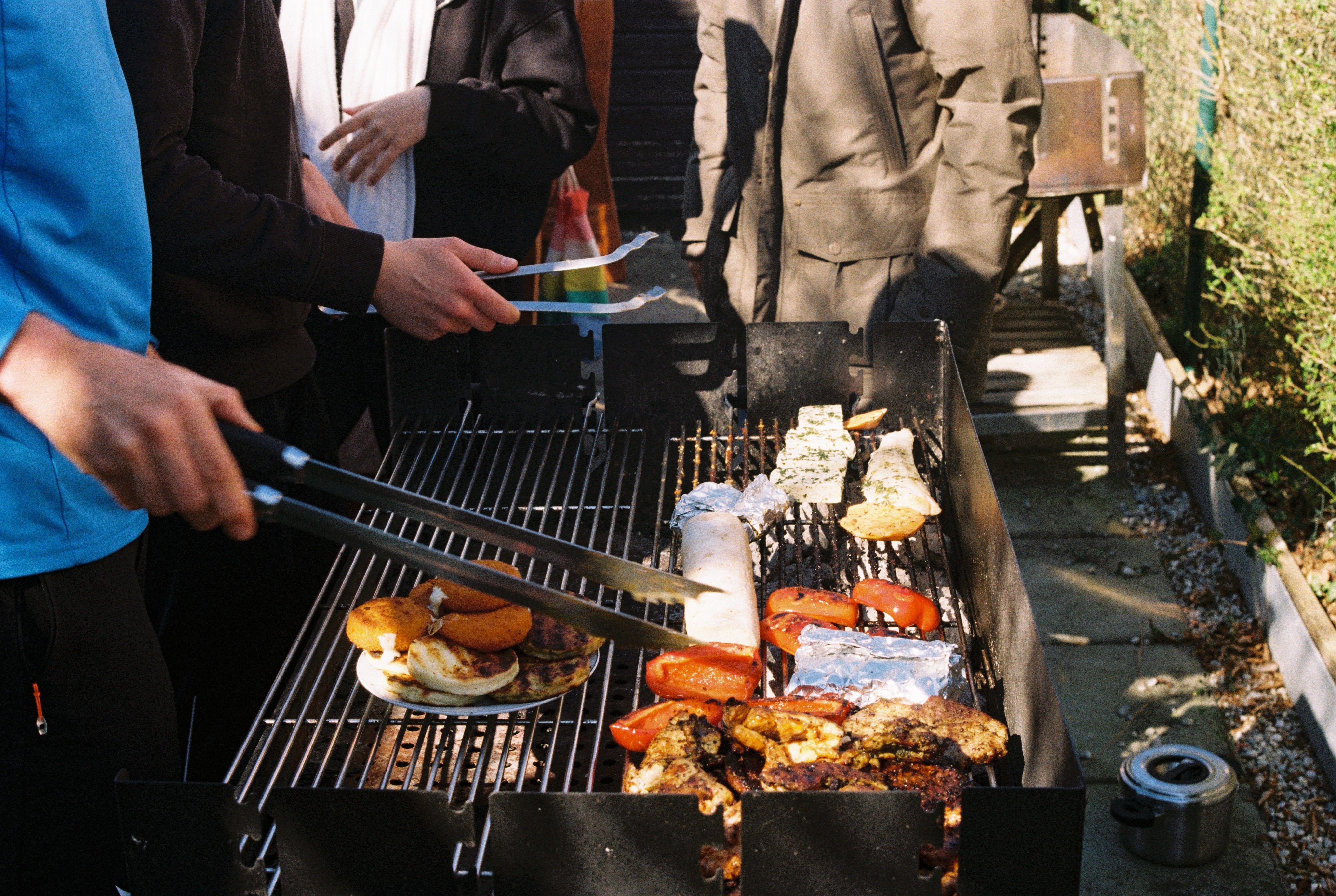 Männer grillen bei einer Grillparty draußen verschiedene Speisen | Quelle: Pexels