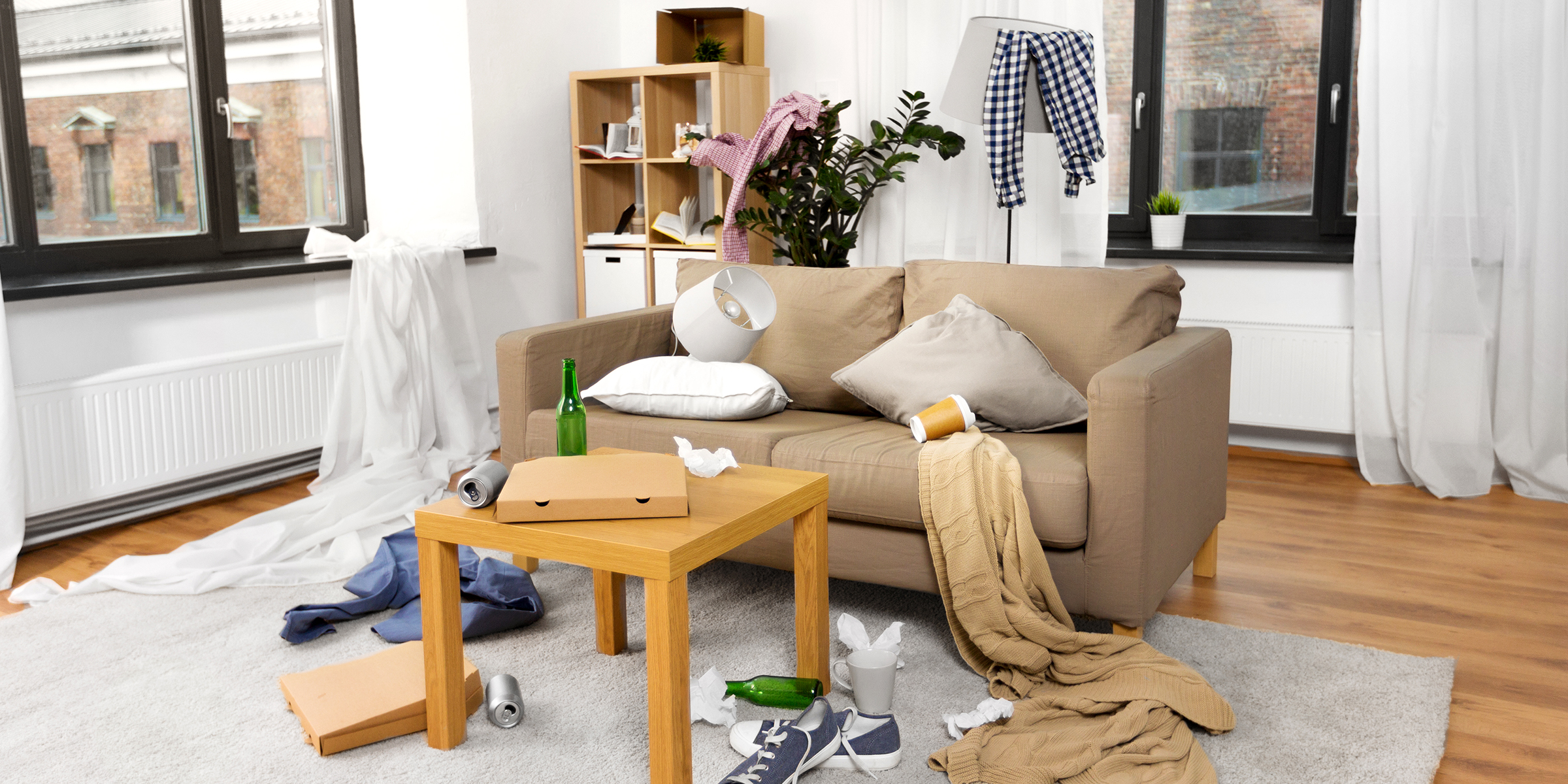 Ein unordentliches Wohnzimmer, in dem Essensboxen, Kleidung und Müll verstreut sind | Quelle: Shutterstock