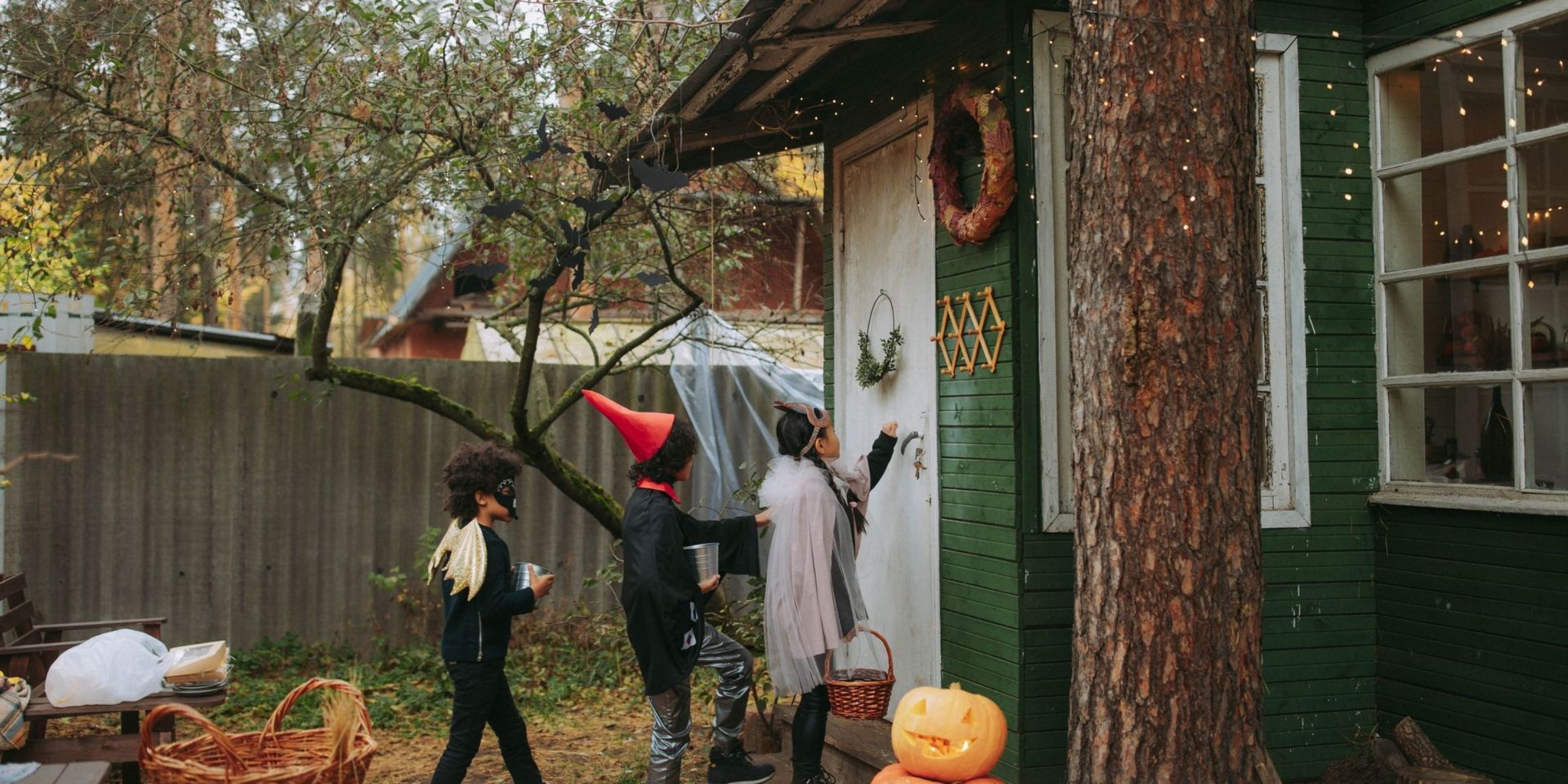Kinder in Halloween-Kostümen, die an einem geschmückten Haus „Süßes oder Saures“ sagen | Quelle: Pexels